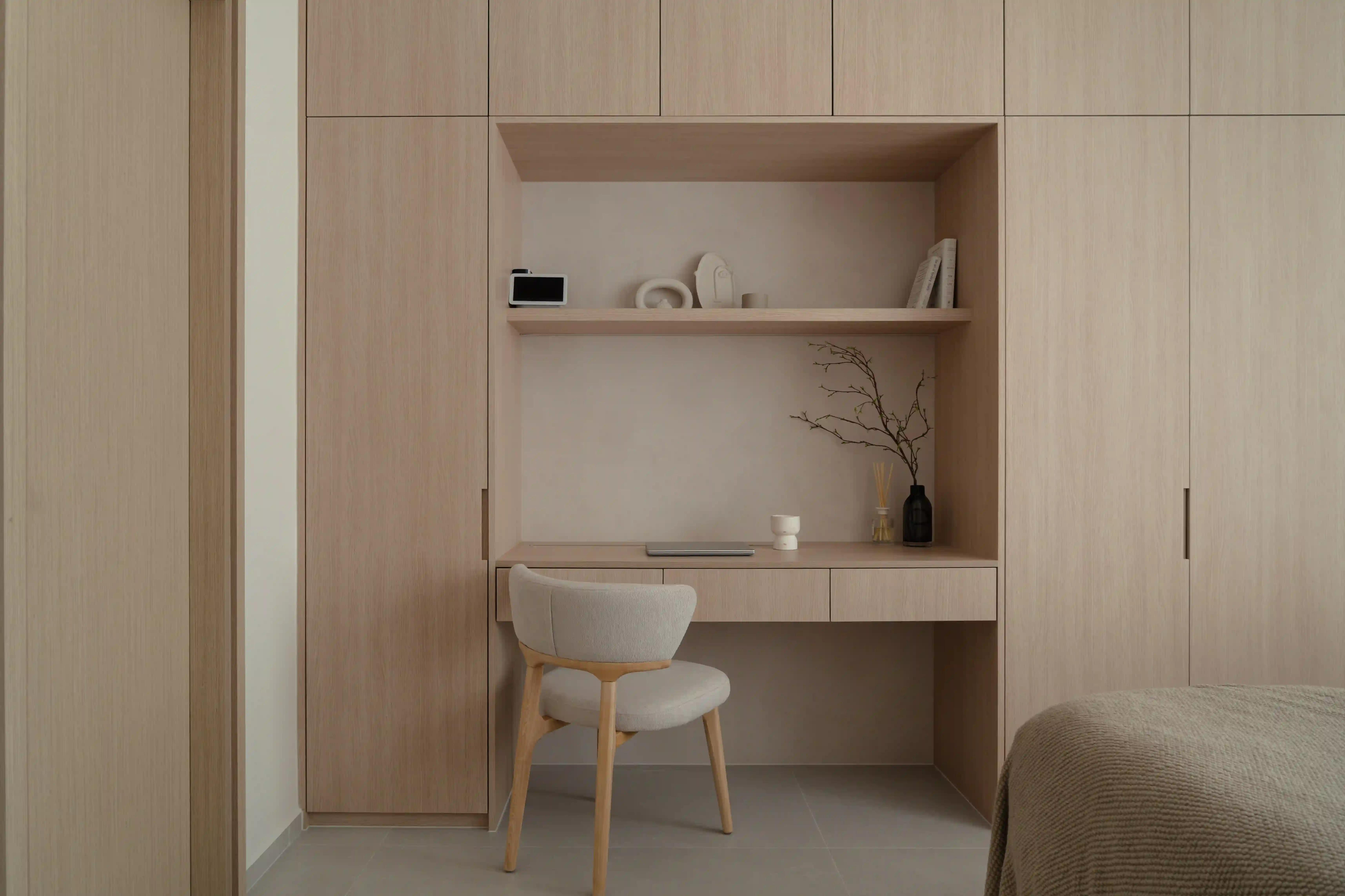 Scandinavian home interior design bedroom study nook with light wood built-ins, open shelf and upholstered chair.