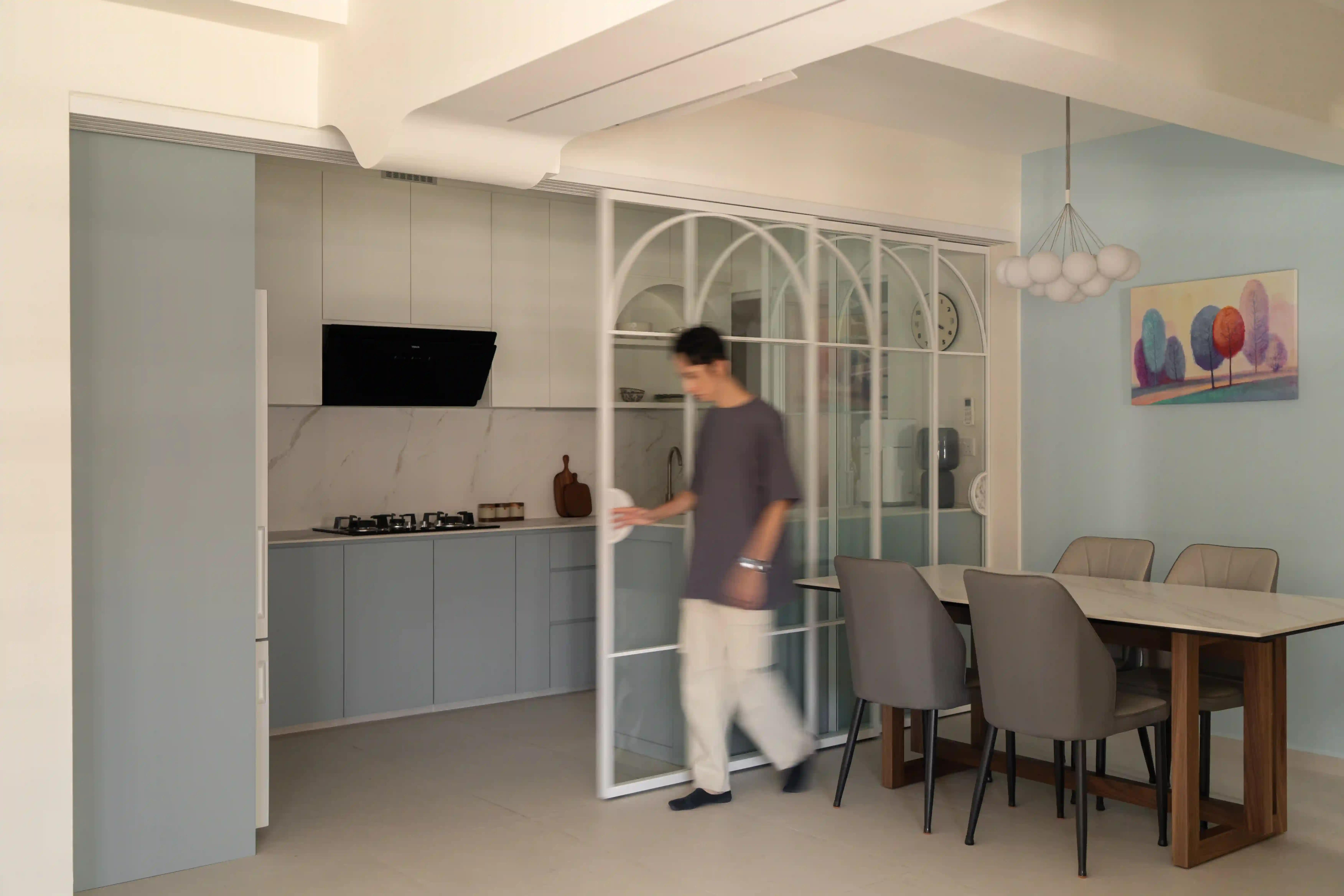 Scandinavian home interior design kitchen with arched glass sliding doors and soft blue cabinets by dining area.