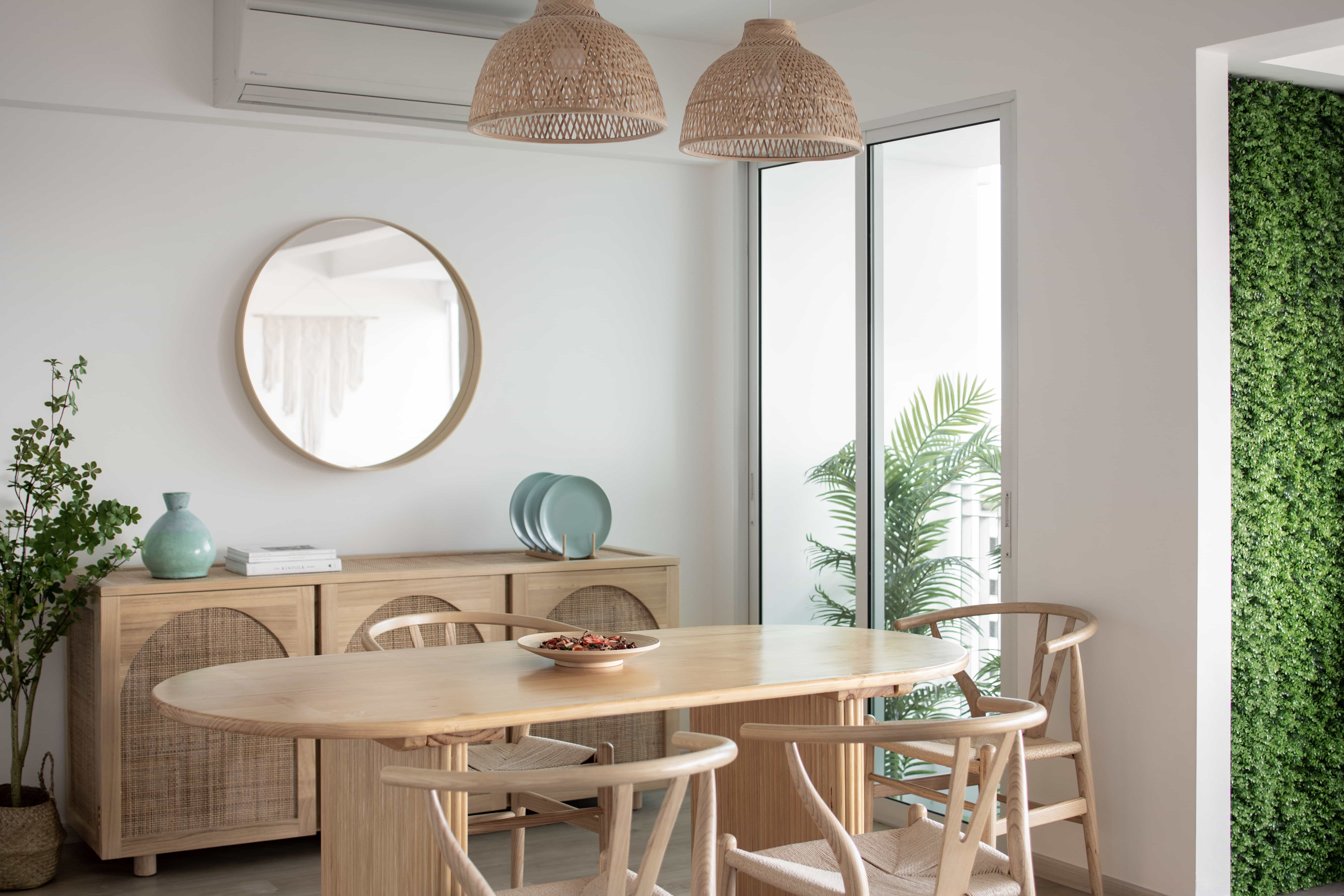 Modern dining area with natural light, featuring a wooden dining table and wicker pendant lights.