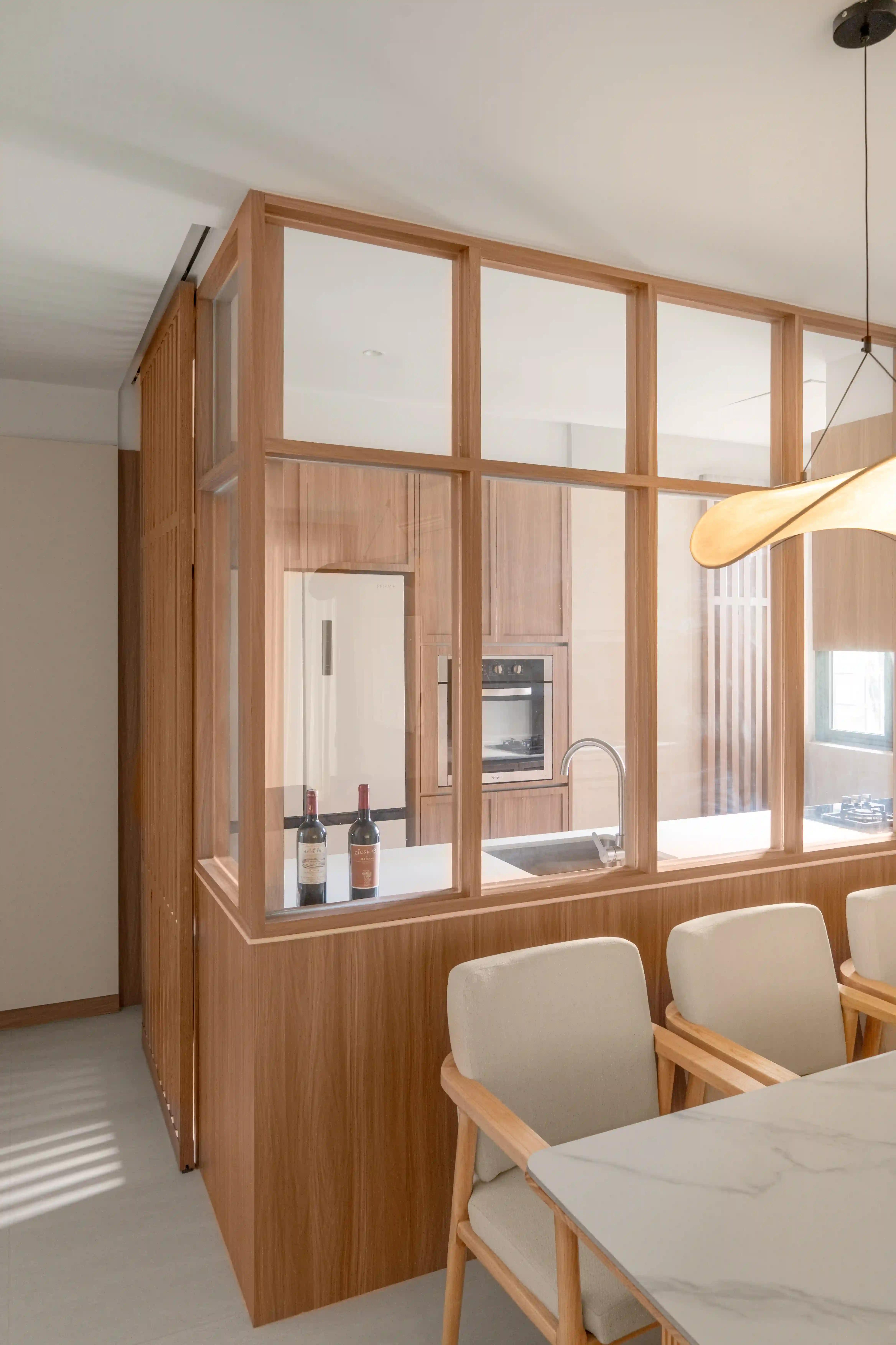 Scandinavian home interior design kitchen framed by glass-and-wood partition beside marble dining table.