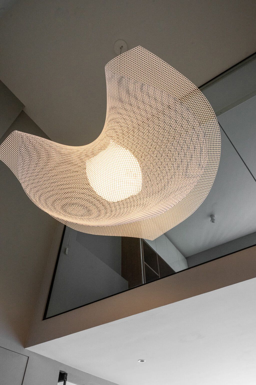 Contemporary loft lighting with a sculptural mesh pendant lamp, enhancing the modern aesthetic of high-ceiling interiors
