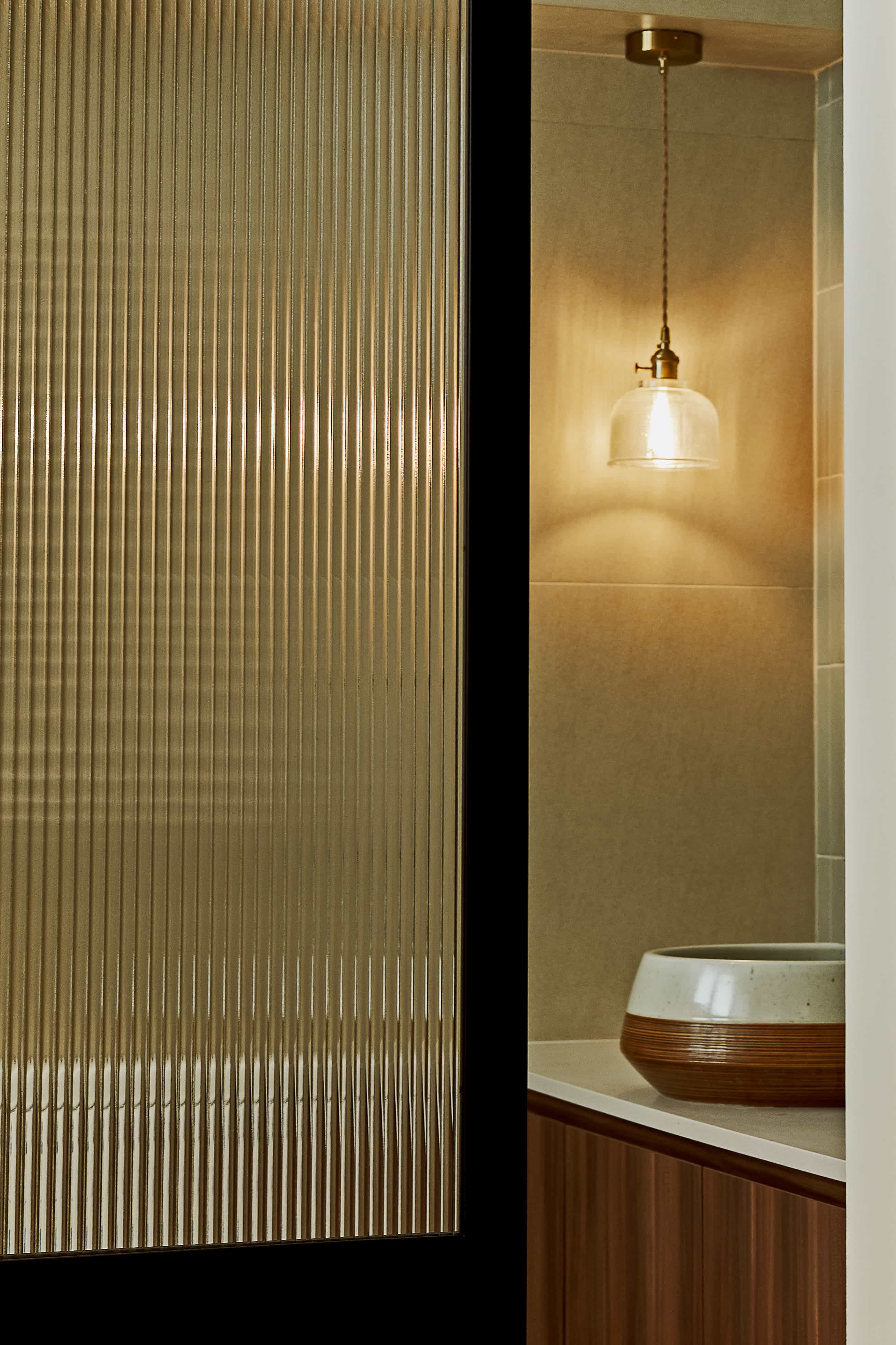 Close-up of a frosted glass bathroom door with a hanging light fixture illuminating the area.