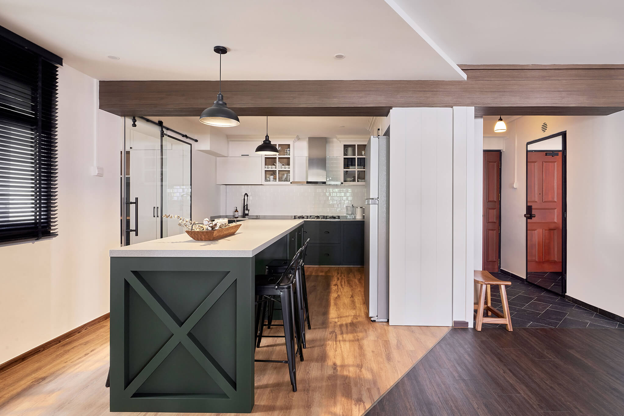 Modern open-concept kitchen with contrasting dark wood and white elements, industrial-style pendant lighting, and a green island centerpiece in a contemporary home.