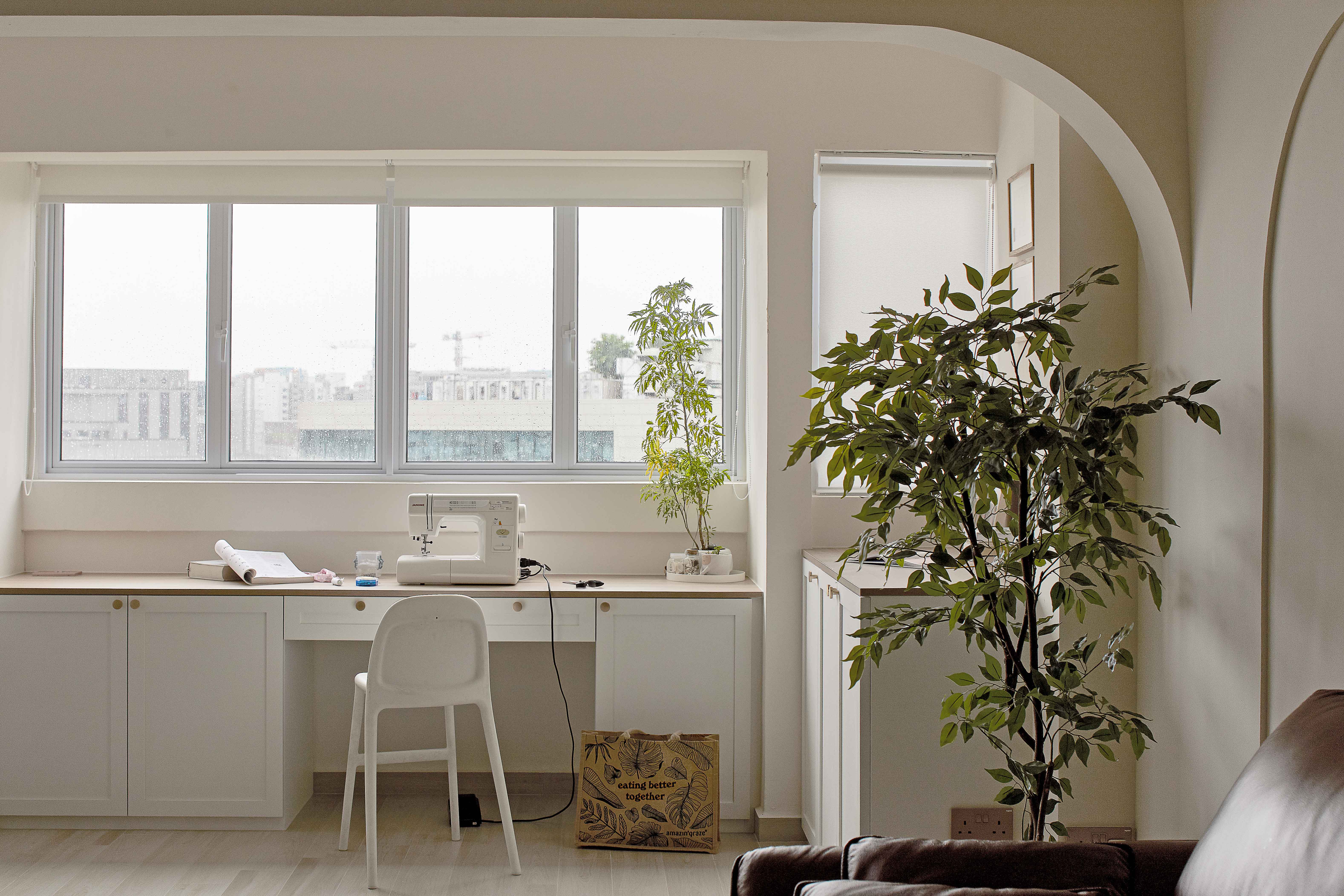 Scandinavian home office with indoor plants, white desk, and large windows for natural light.