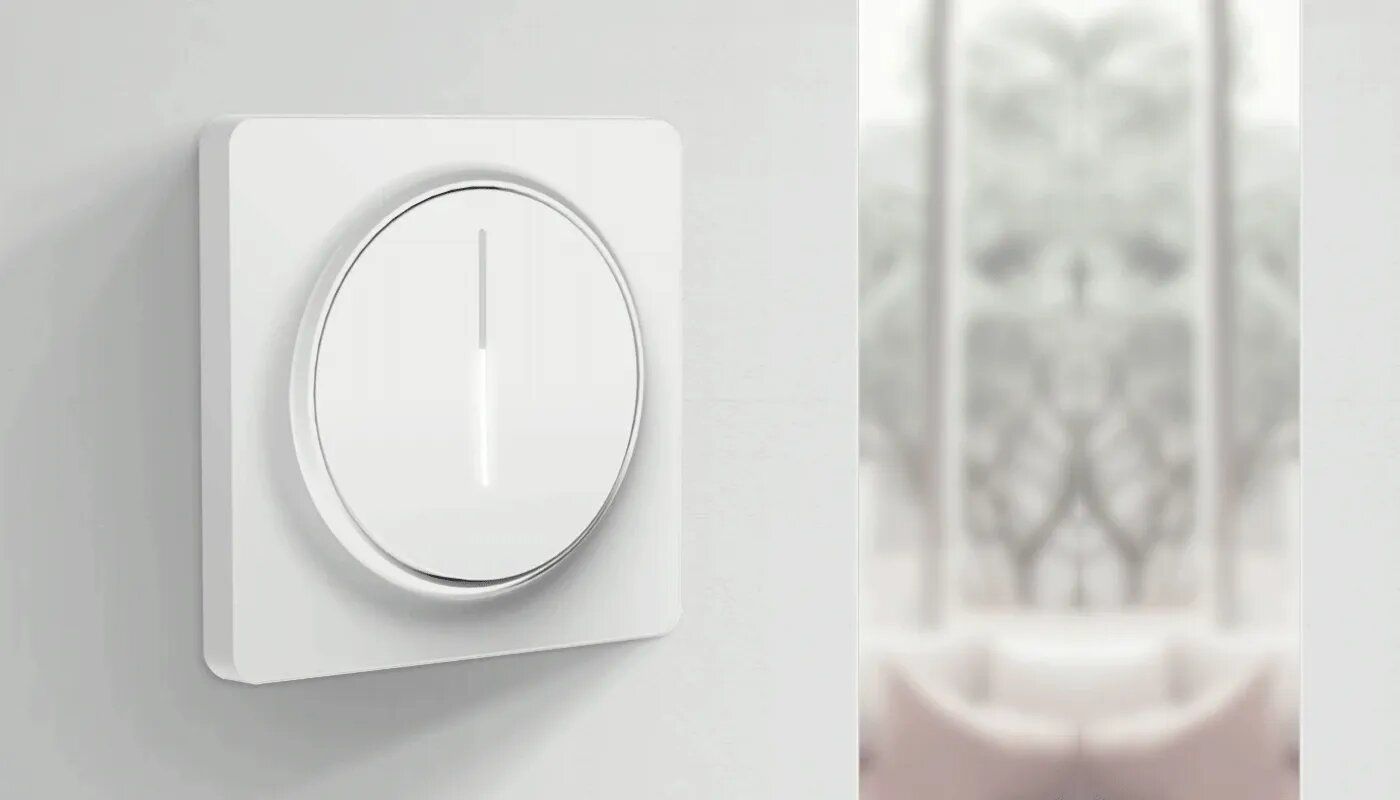 Minimalist smart dimmer knob on a white wall adjusting living-room brightness