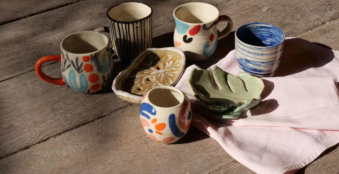 Handcrafted ceramic tableware collection basking in the sun, featuring artisanal mugs and bowls with vibrant patterns, perfect for adding a touch of the Earth element in Feng Shui home design.