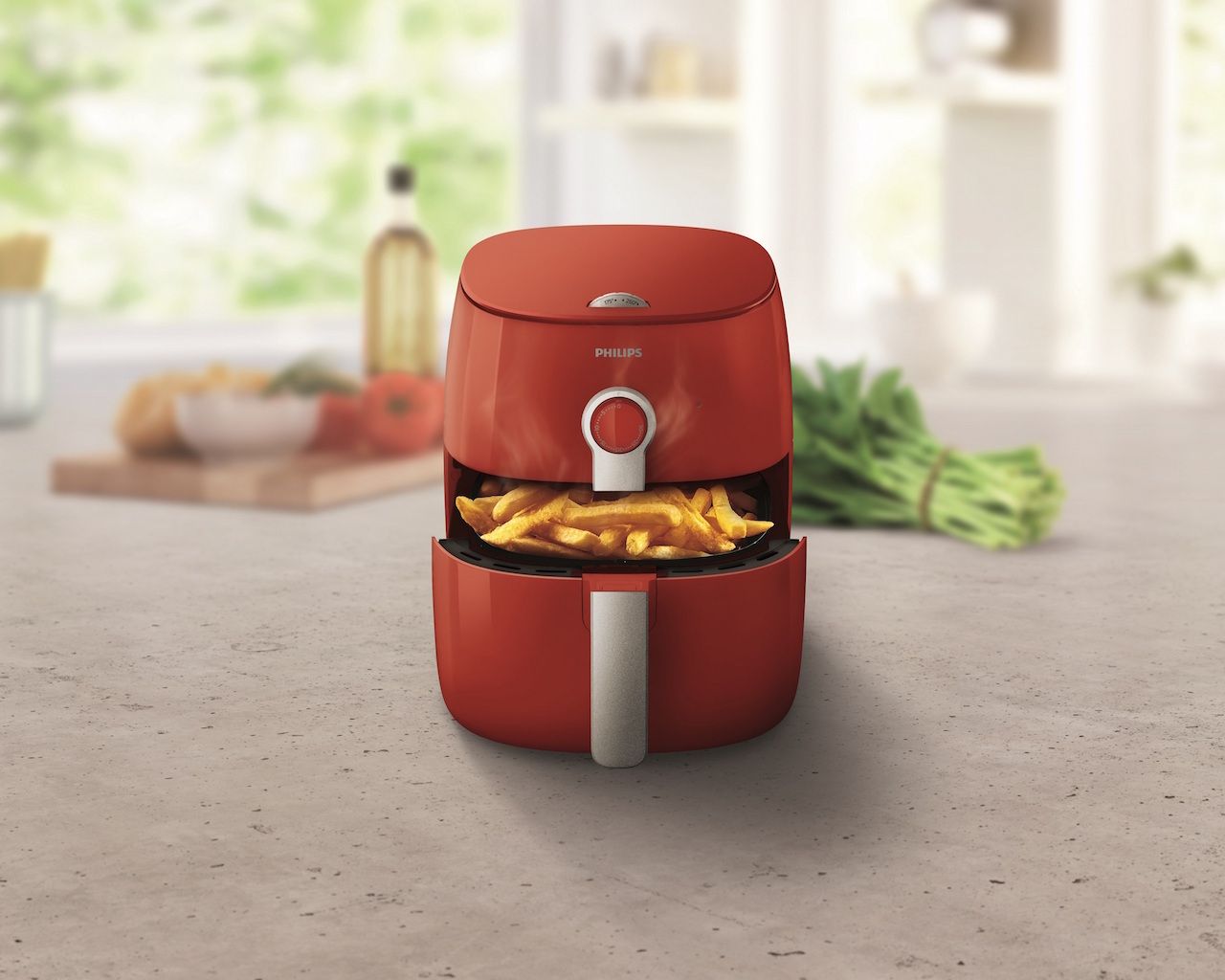 Red Philips air fryer showcasing fries cooked with minimal oil.