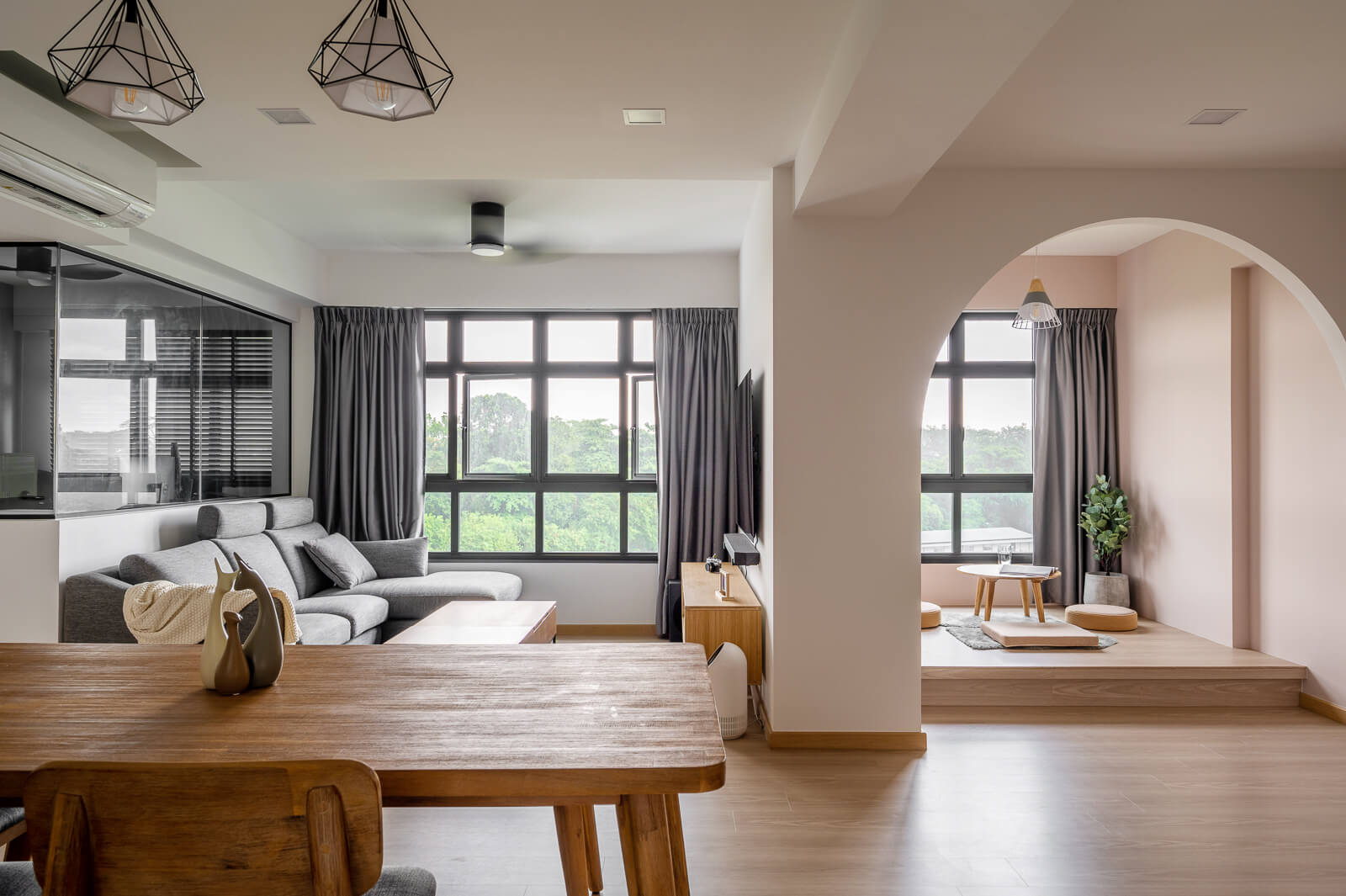 Scandinavian-inspired dining room with a wooden table, modern lighting fixtures, and large windows with dark curtains.