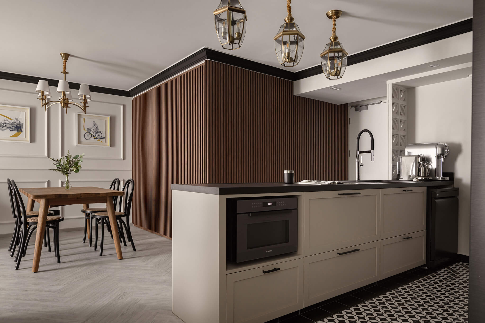 Chic transitional kitchen design with taupe cabinetry, herringbone wood floor, and brass pendant lighting over a classic dining set, featuring a sleek built-in microwave and espresso machine.