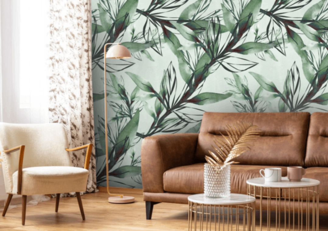 Living room with leather sofa, abstract leaf mural, armchair and round nesting tables.