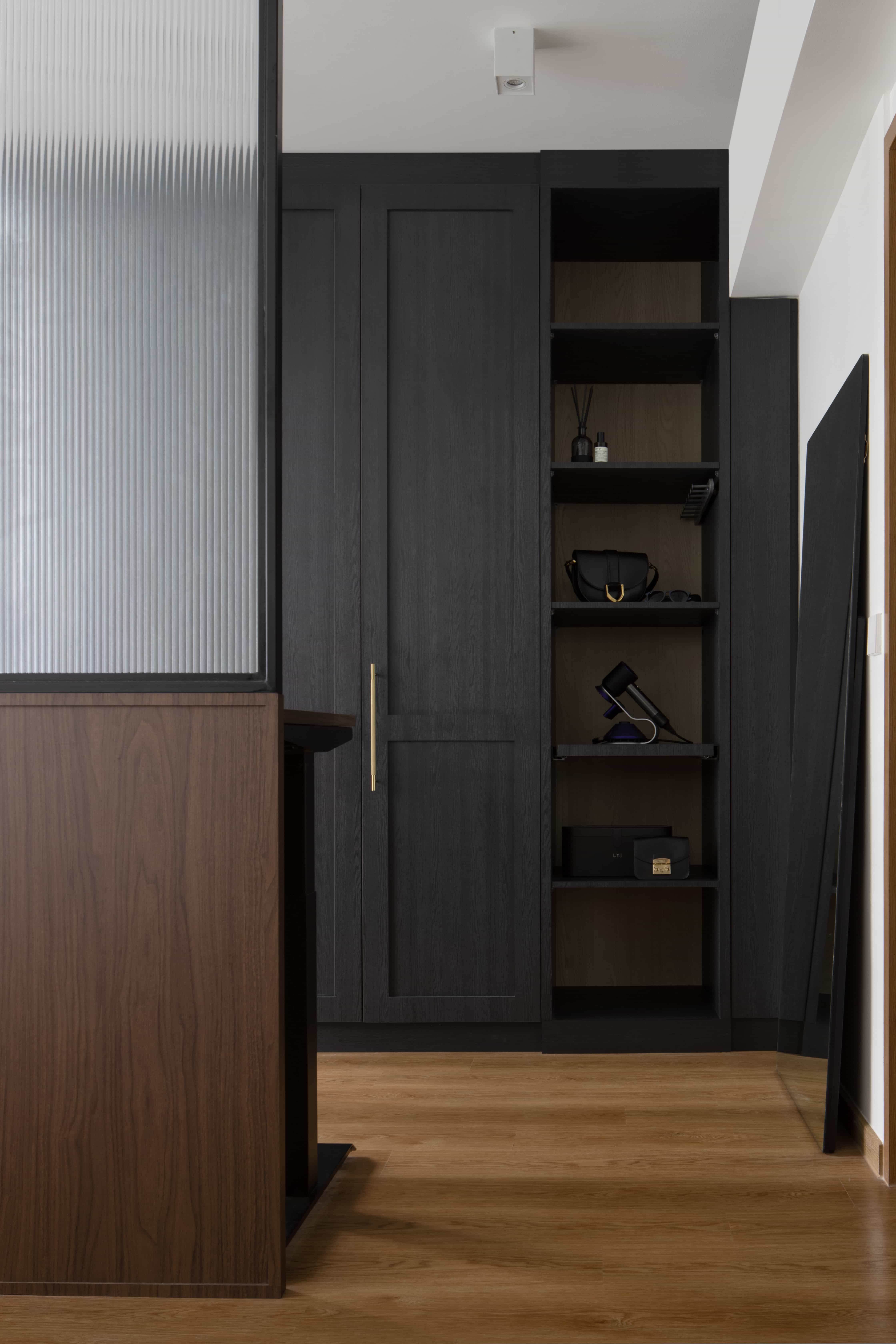 Dark wood wardrobe with open shelves displaying accessories in a stylish room.