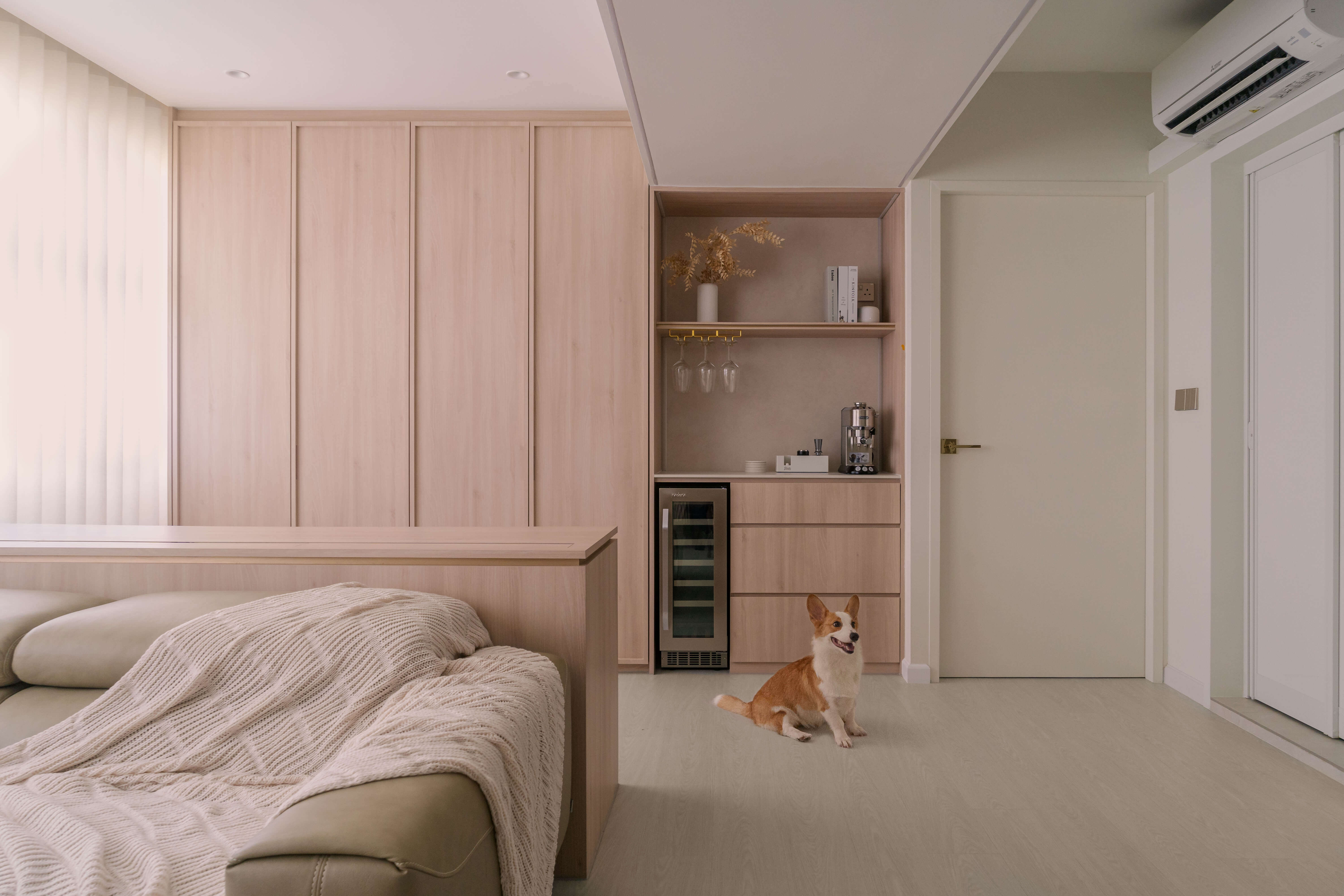 A pet-friendly corner featuring light wood tones, a cozy couch, and a happy dog in a minimalist design.