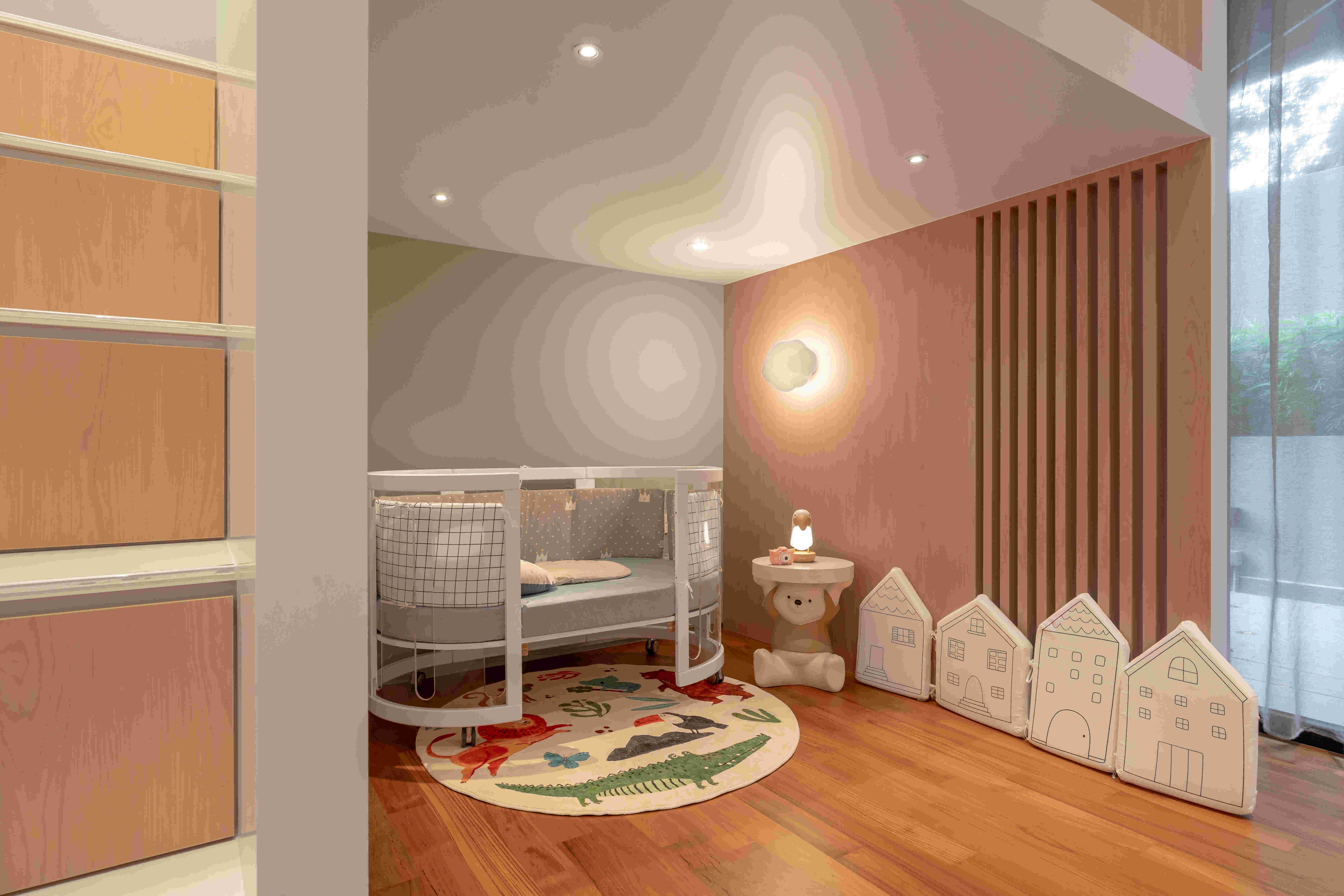 Soft pastel nursery with circular crib, playful animal rug, cloud sconce, and warm wood flooring designed for safe toddler play.