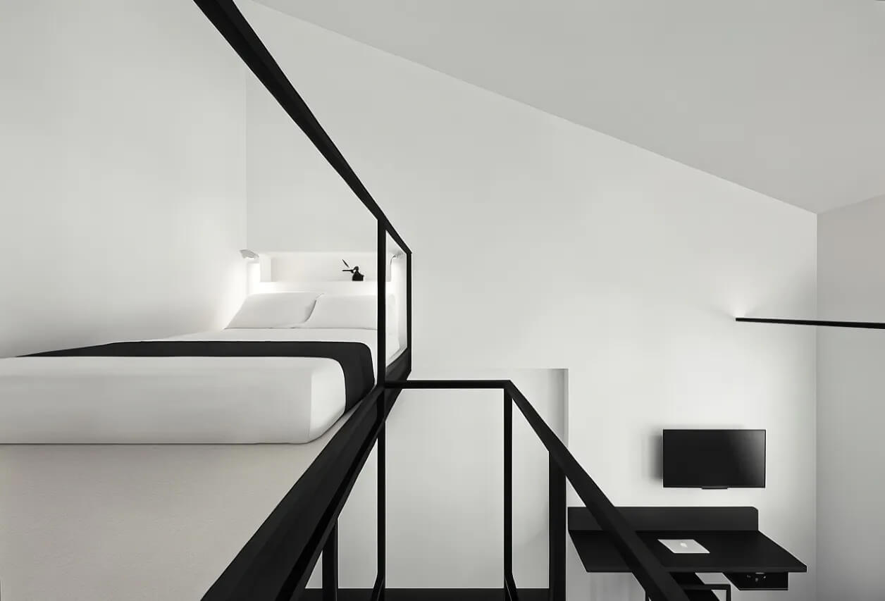 Sleek and modern loft bedroom with monochromatic color scheme, featuring a black metal staircase leading to a cozy sleeping area