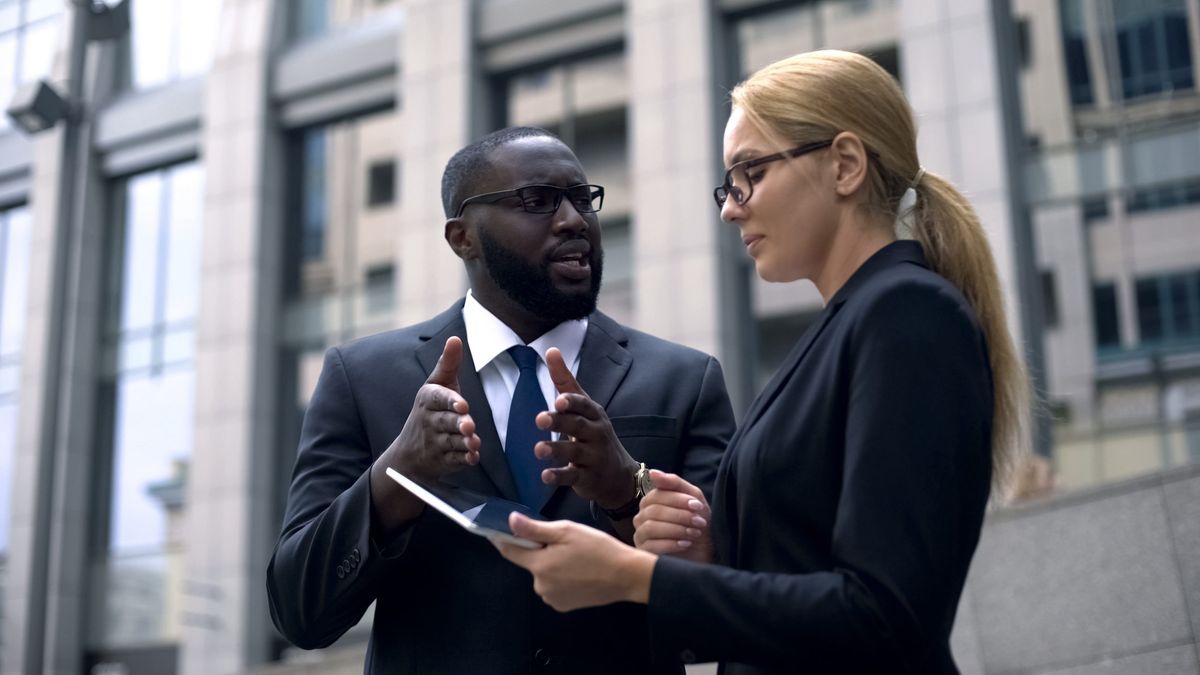 Client convincing lady investor of project profitability, shows income on tablet