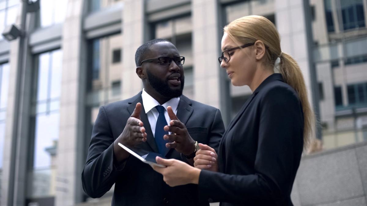 Client convincing lady investor of project profitability, shows income on tablet