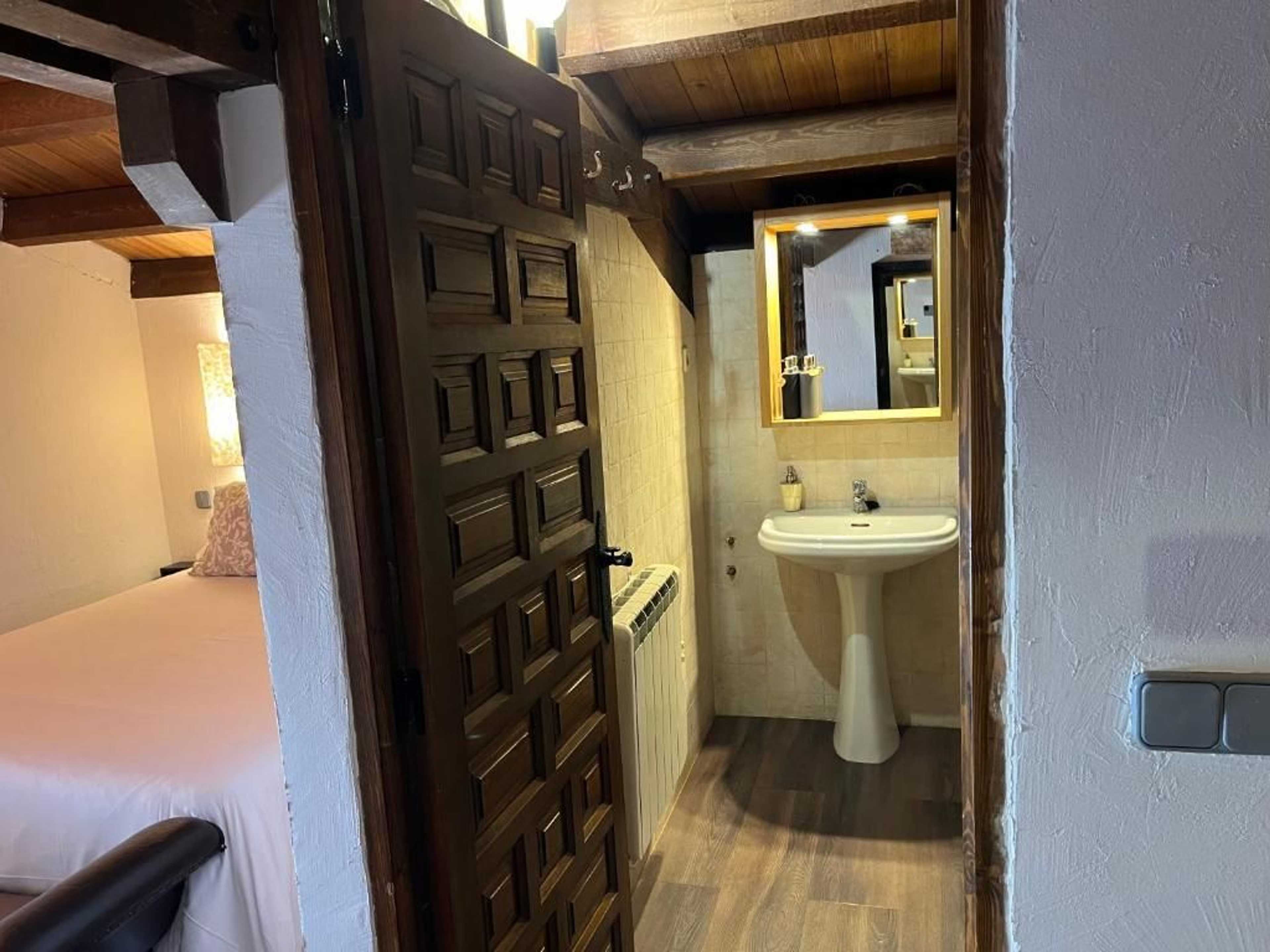 Entrada al baño con puerta tallada de madera