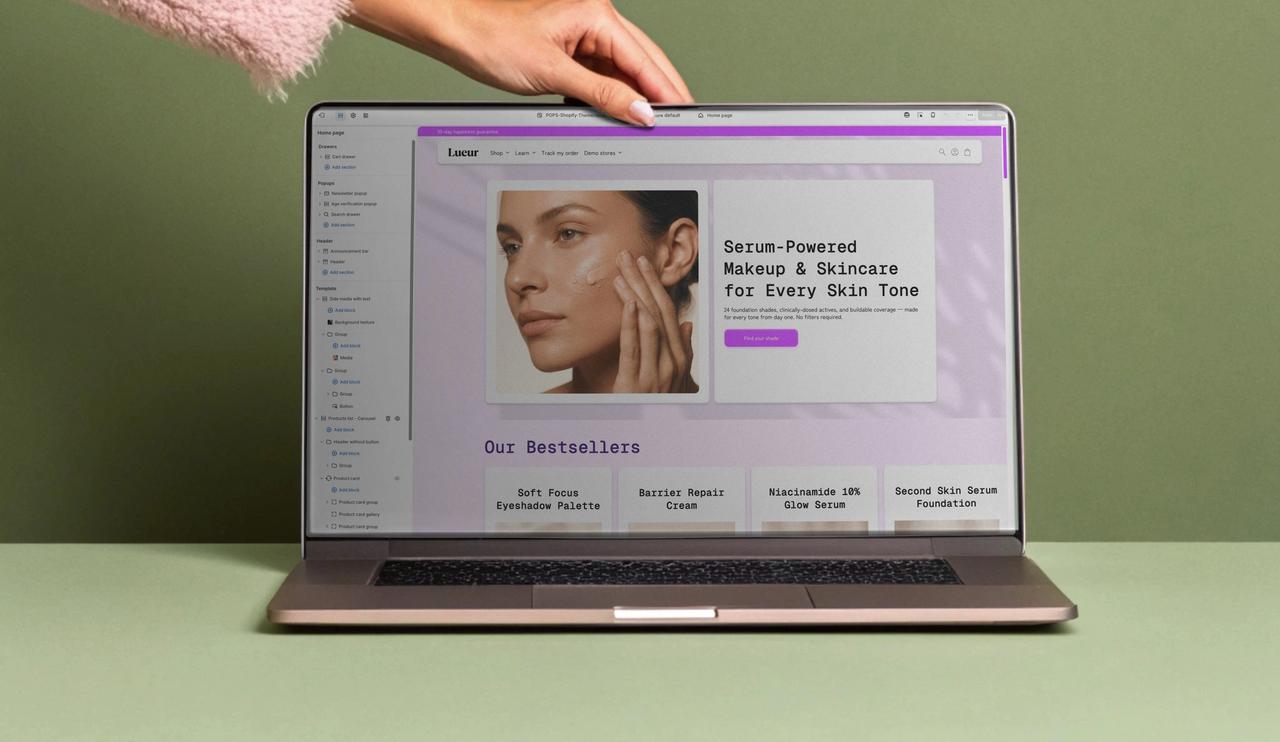 Woman holding a laptop showing the Shopify Theme Editor with the Pops Theme.