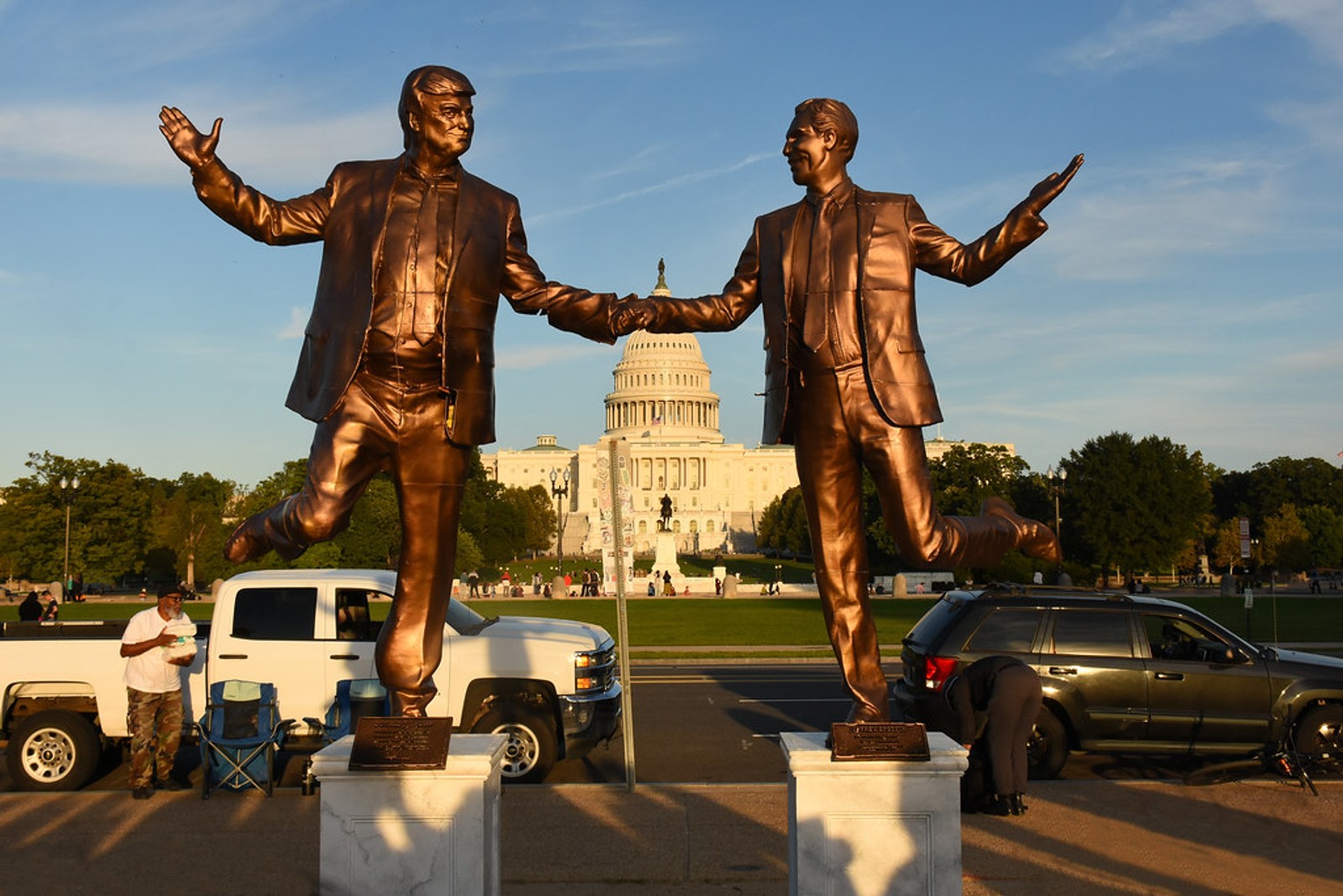 Bronze statues of Donald Trump and Jeffrey Epstein dancing and shaking hands near the U.S. Capitol.