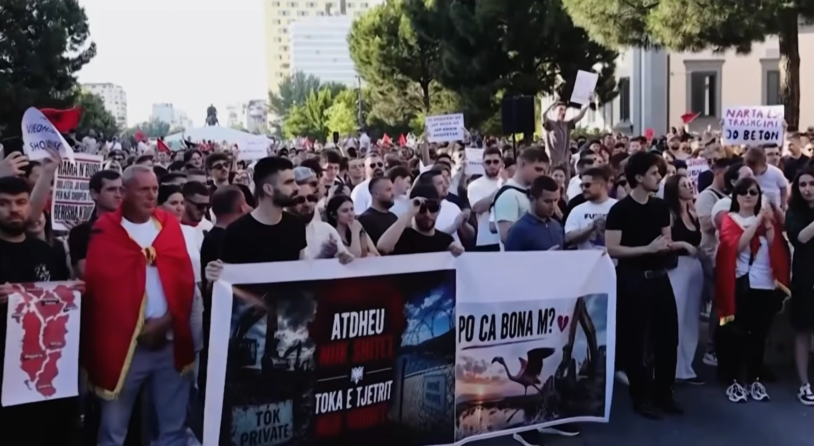 Large crowd gathered at a protest in Albania, with demonstrators holding banners and signs during a public rally in a city street.