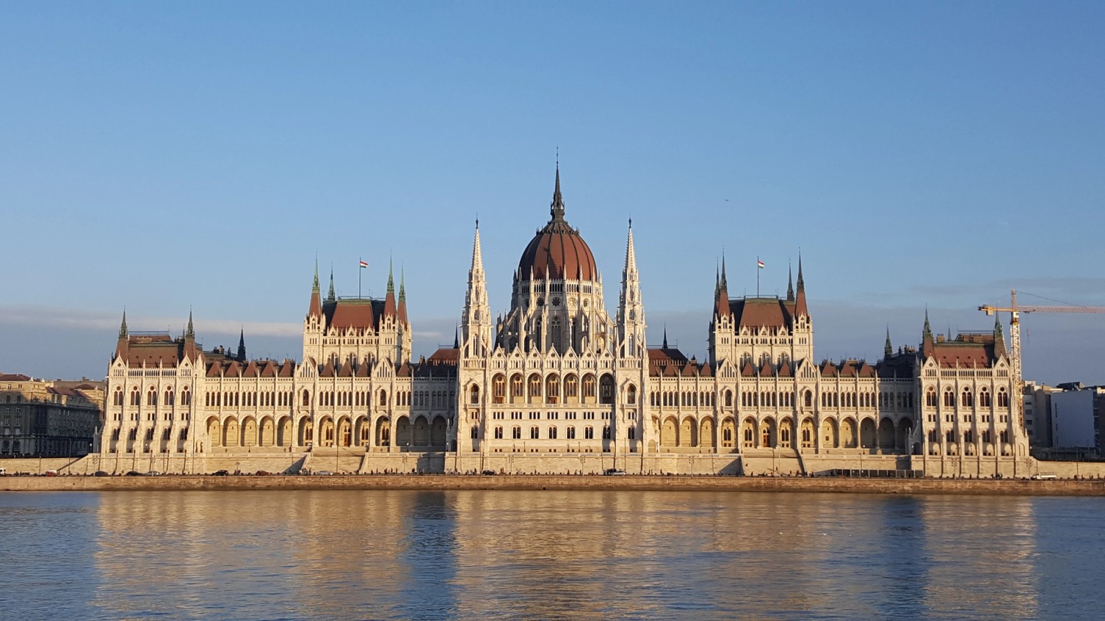 The Hungarian Parliament Building in Budapest, seen across the Danube River with its distinctive dome and neo-Gothic façade.
