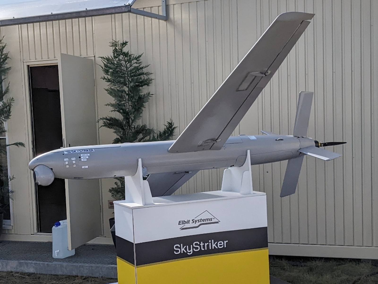 Elbit Systems SkyStriker loitering munition drone displayed on a stand, showing its fixed wings and rear propeller design.