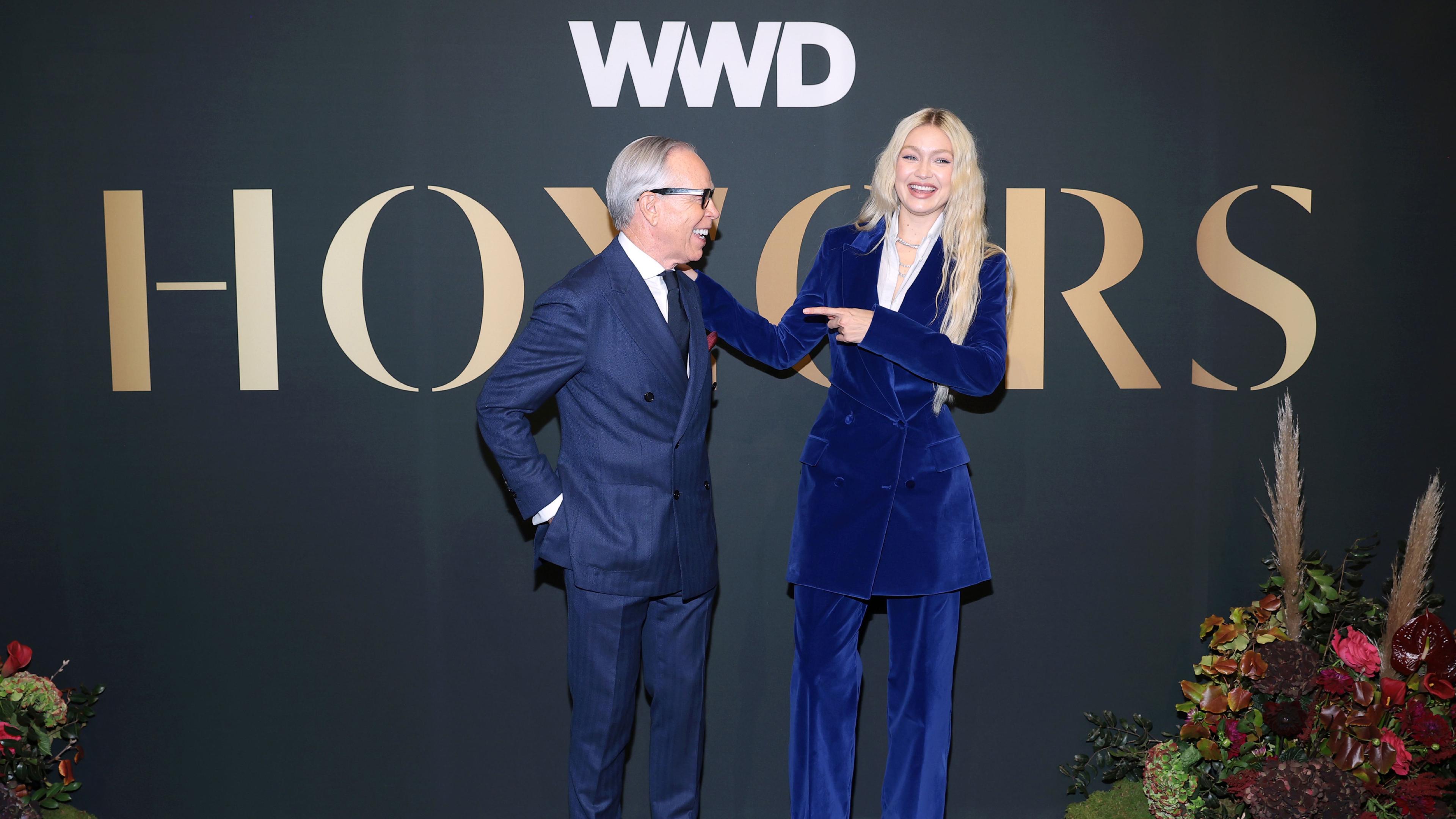 Tommy Hilfiger and Gigi Hadid standing in front of the WWD Honors stage backdrop