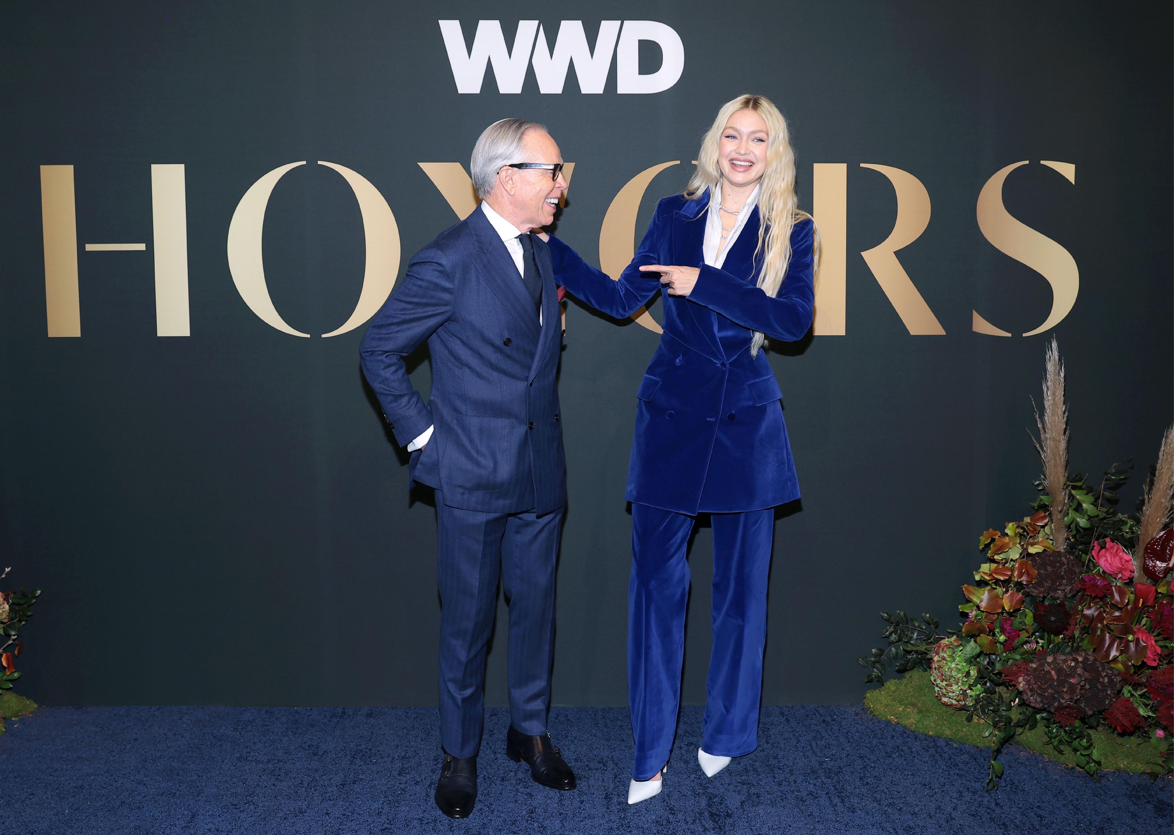 Tommy Hilfiger and Gigi Hadid standing in front of the WWD Honors stage backdrop