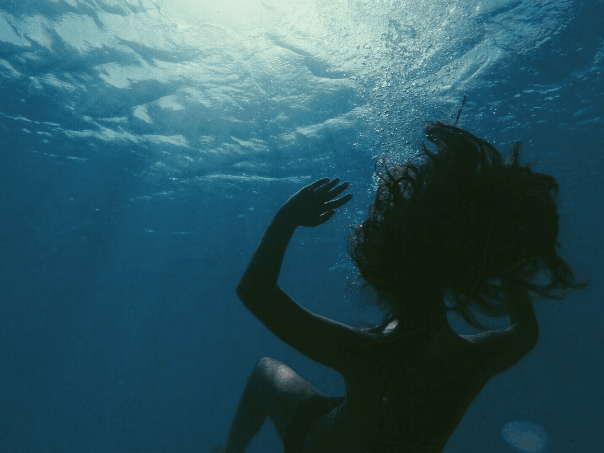 A lone figure suspended underwater, capturing the quiet weight of depression.