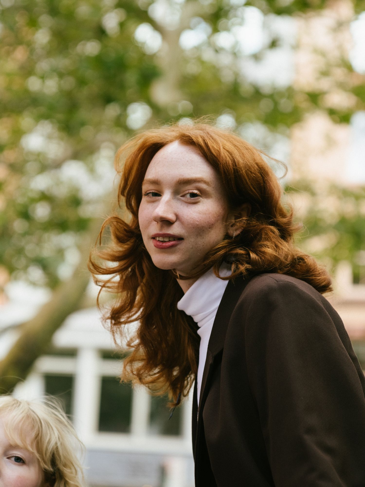 Portrait of a red-haired woman in a brown blazer outdoors