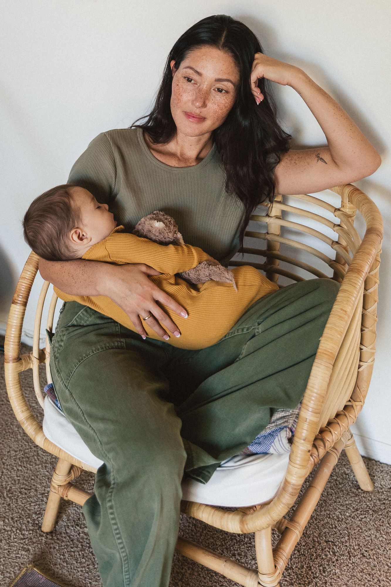 Mother cradling her sleeping baby in a wicker chair