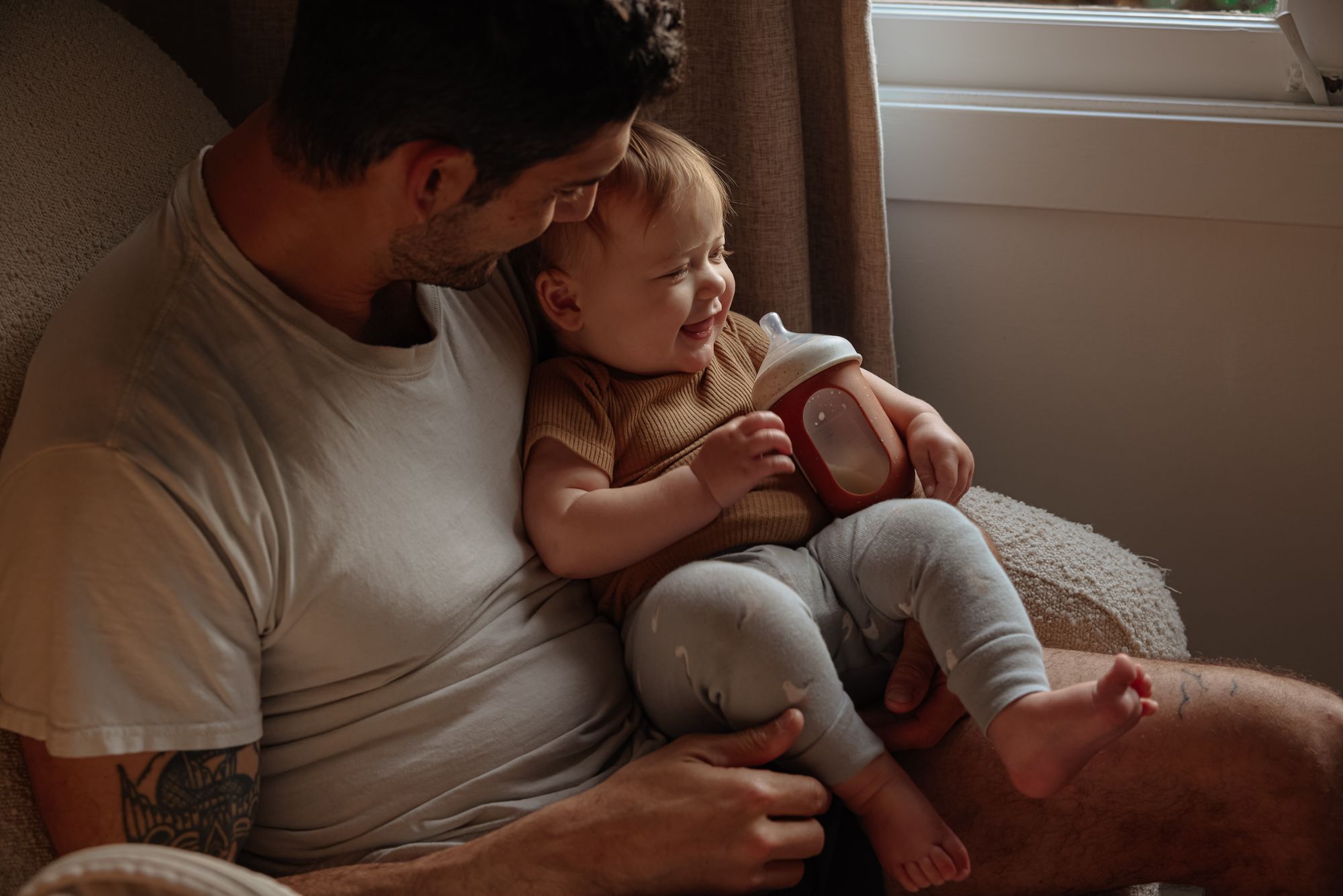 Father sitting in an armchair smiling with his baby