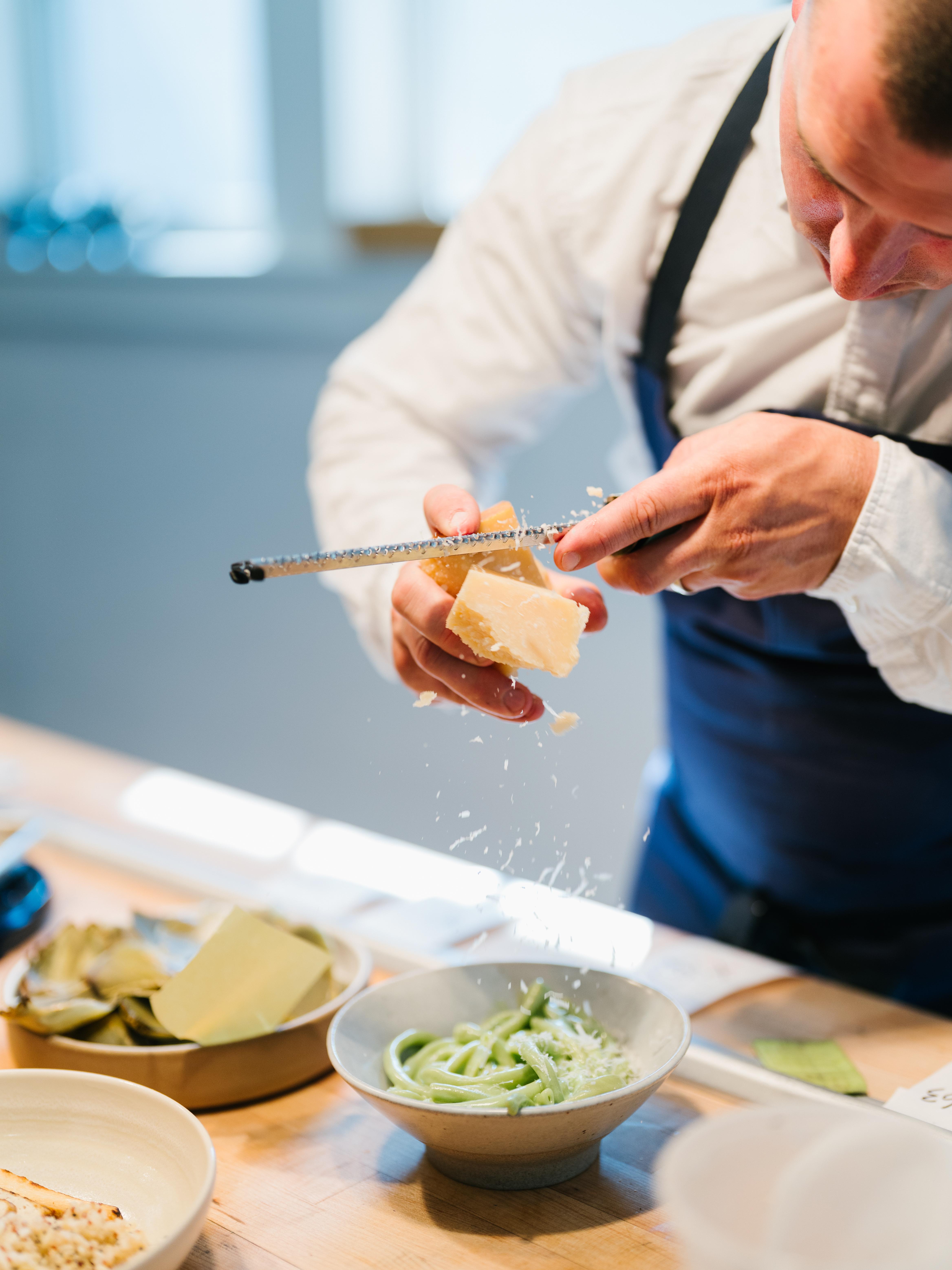 Chef Elliot Bell grating parmesan on summer peas.