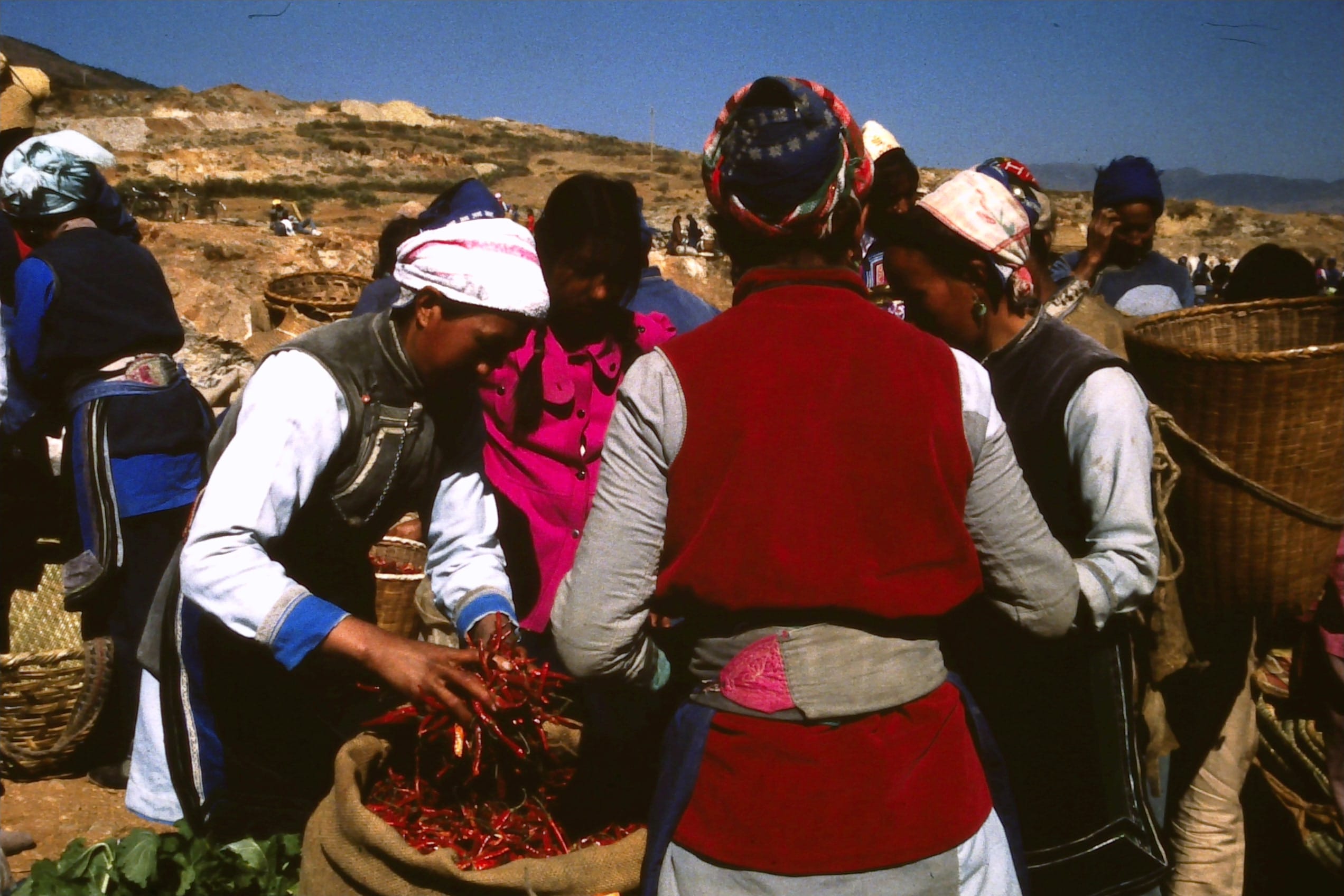 Open market in the mountains outside Dali. Women sampling red Chillies.