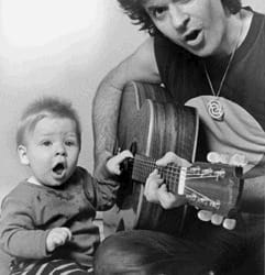 Rory playing guitar with his son Solly by his side.