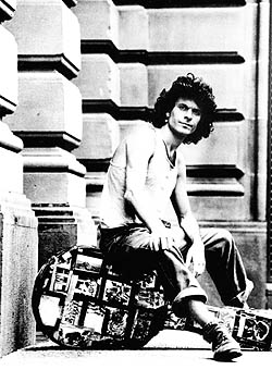 Rory sitting on his guitar case outside a building.