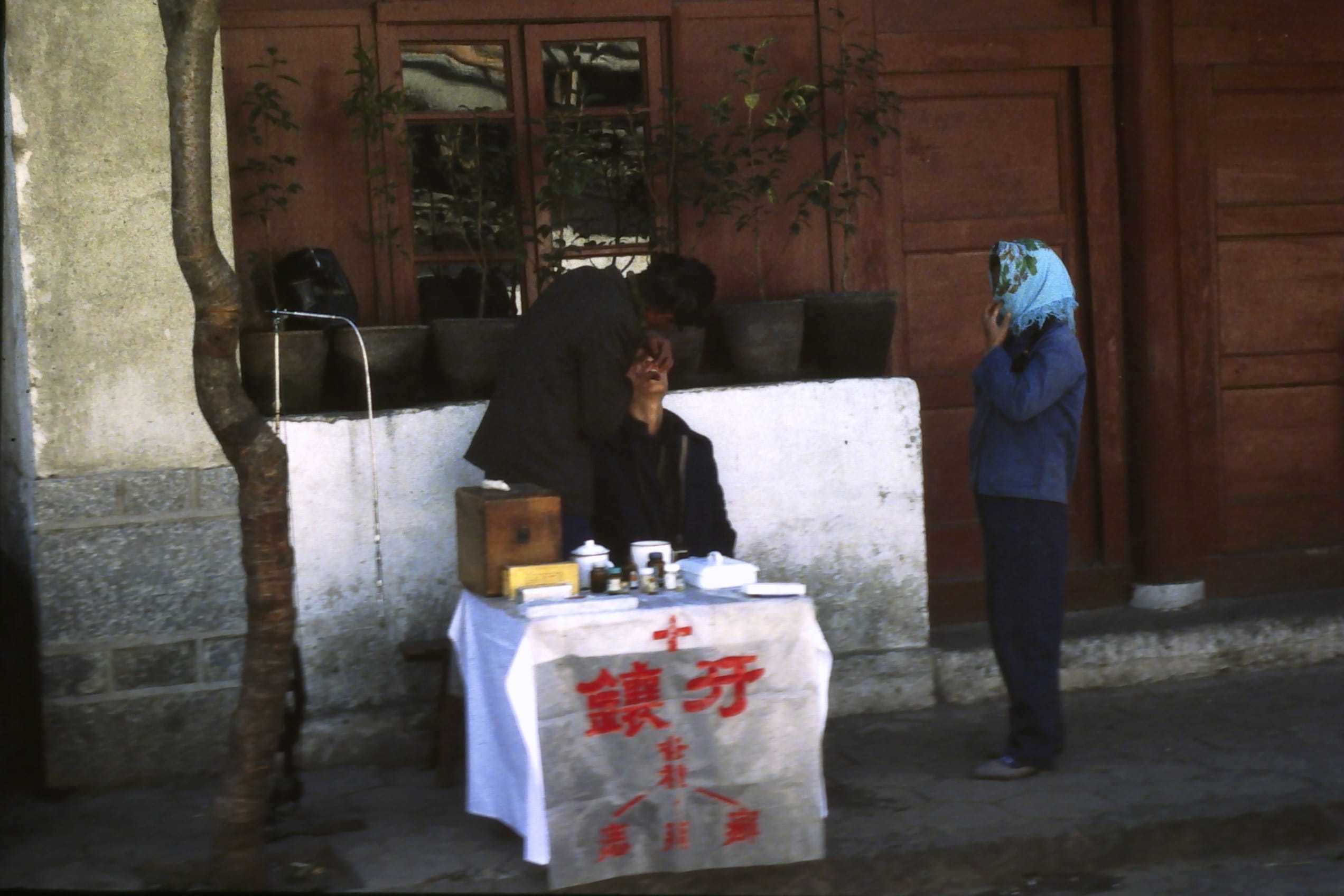 Kunming. Street dentist. Perhaps the woman with the scarf waiting for treatment has a tooth ache