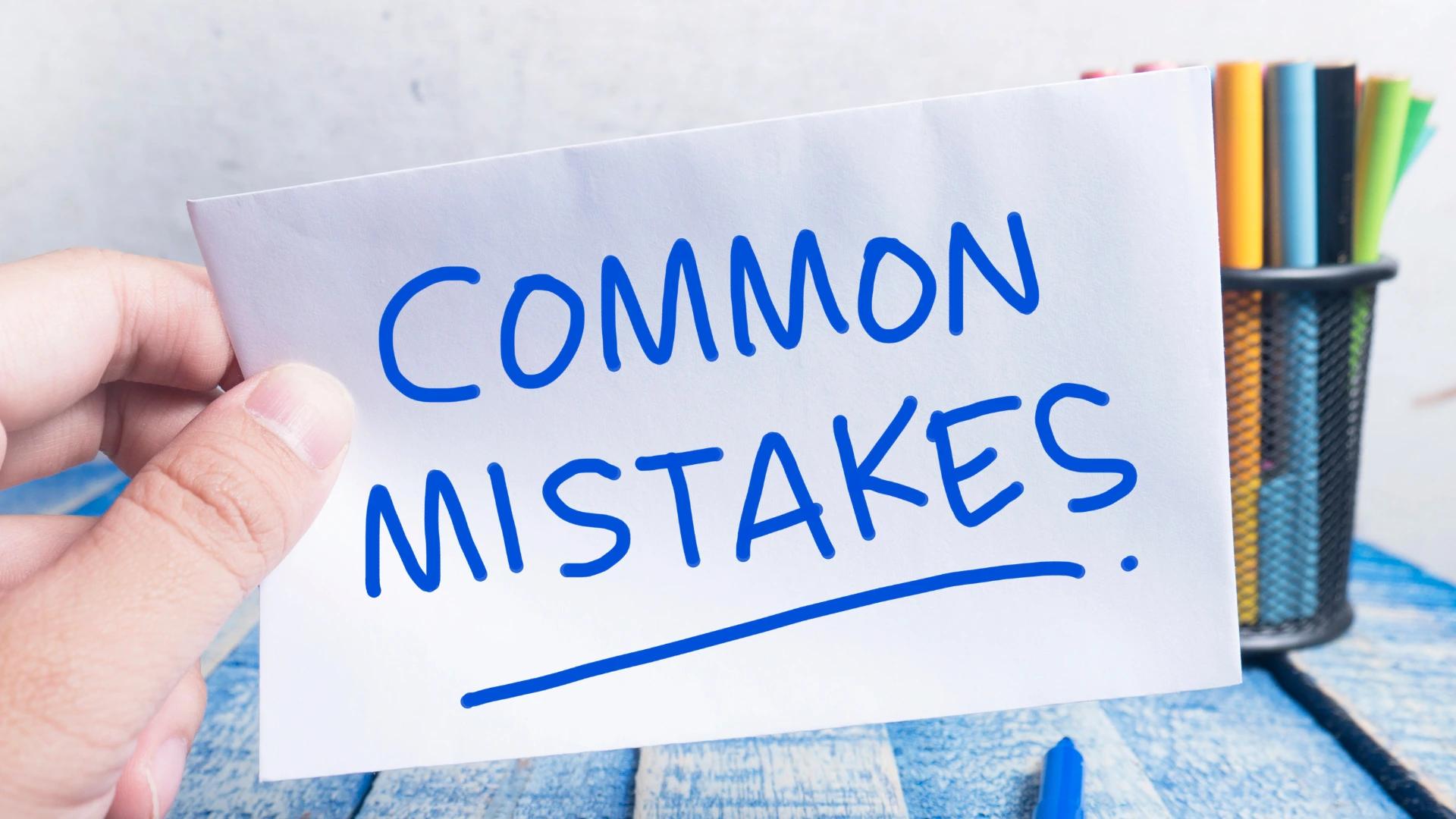 Hand holding a card labeled 'COMMON MISTAKES', symbolizing common errors to avoid in AI developer recruitment at https://codeautomation.ai/