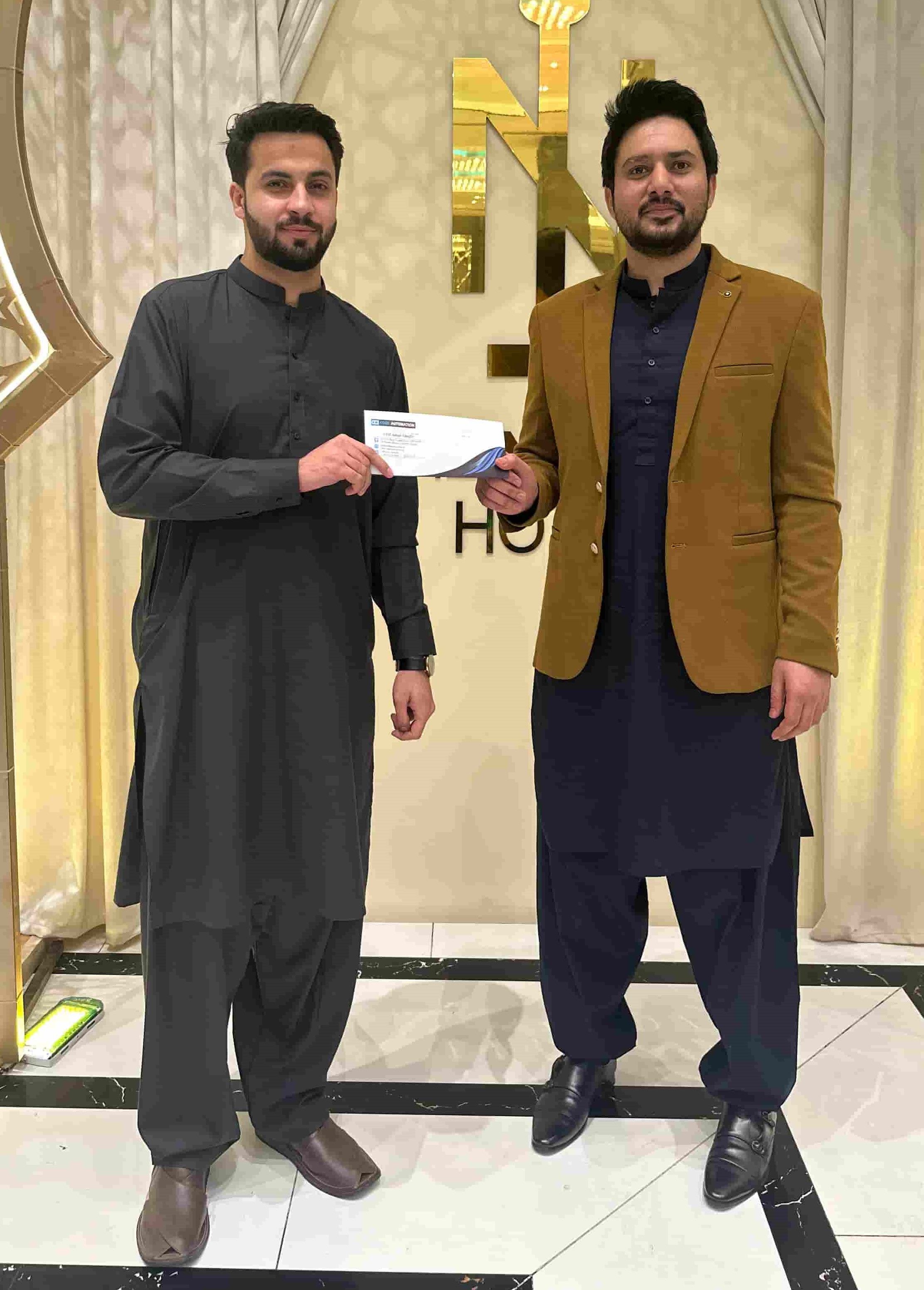 CodeAutomation CEO Adnan Ghaffar presenting a cash prize to an employee at a celebratory event, highlighting the company’s recognition culture.