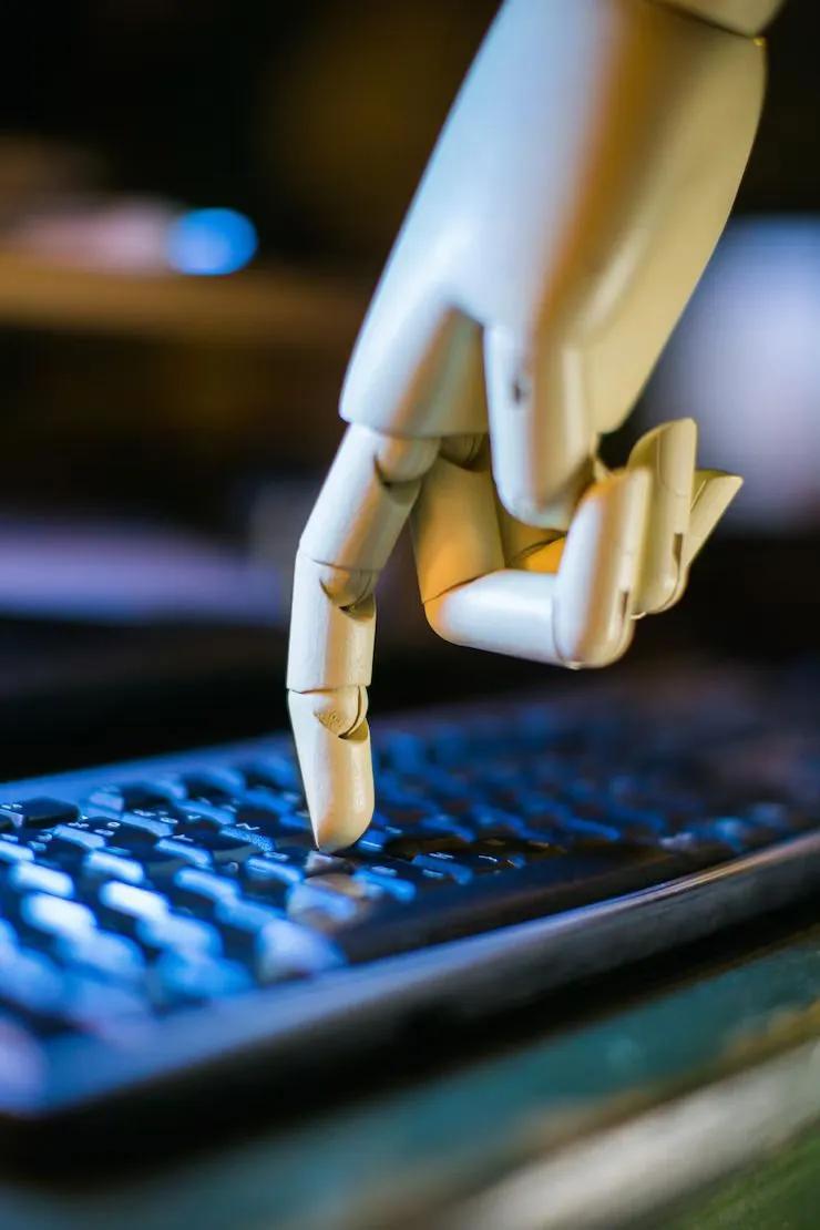 Robot hand typing on a keyboard, representing AI-powered automation and Zoho automation services by CodeAutomation.ai for business process optimization and workflow automation.