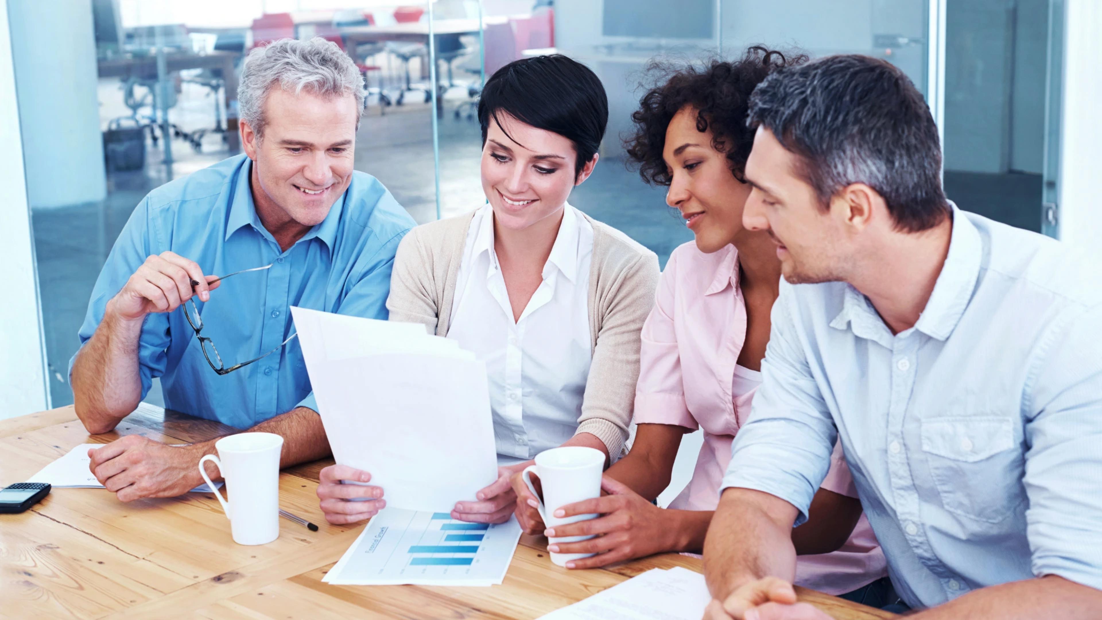 Team of professionals collaborating over business documents, discussing strategies and progress for AI development projects at https://codeautomation.ai/