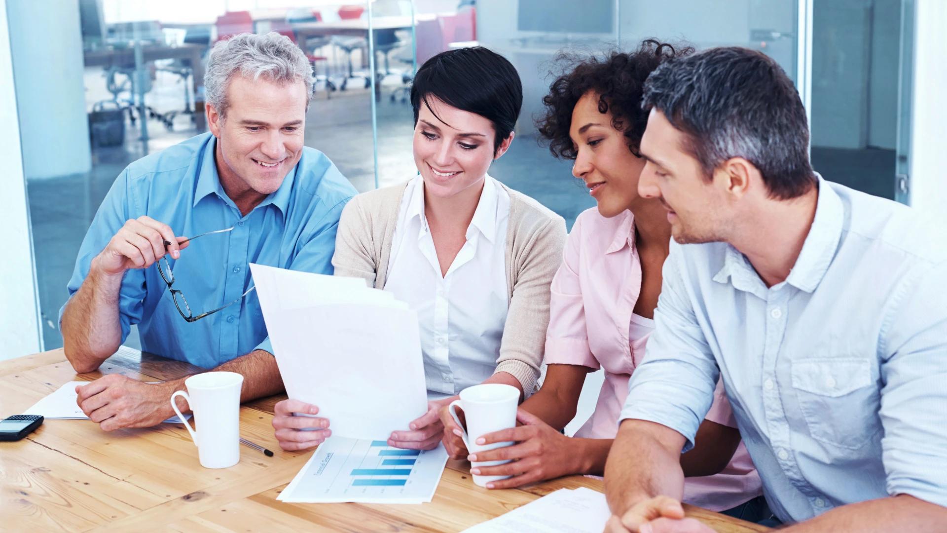 Team of professionals collaborating over business documents, discussing strategies and progress for AI development projects at https://codeautomation.ai/