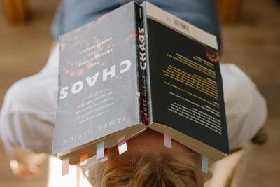 large image of a person with an open book laying on their head