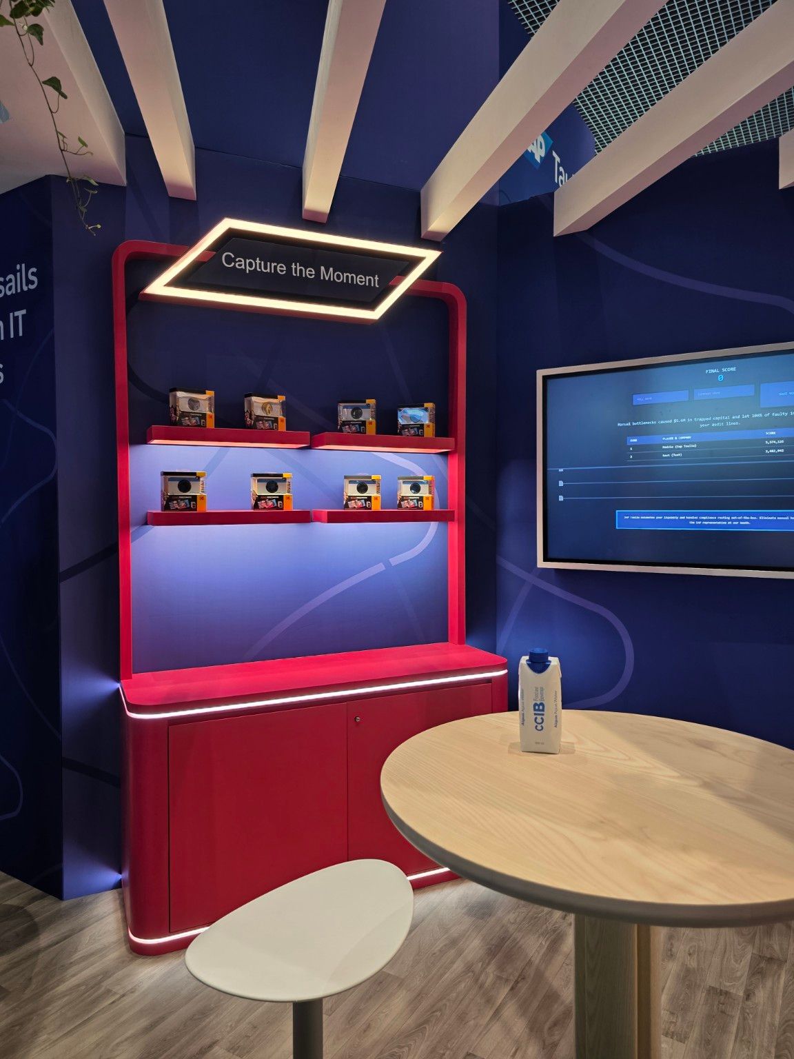 Red display unit with integrated lighting and cameras beside a screen at the SAP Taulia stand