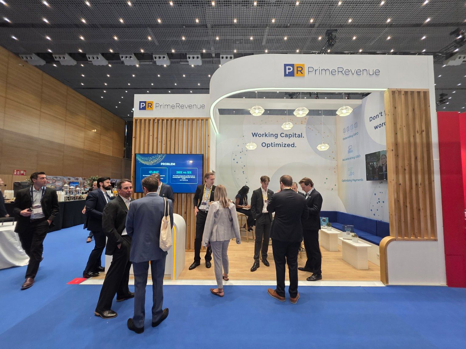 Front view of the PrimeRevenue stand at EuroFinance Barcelona 2026, with an illuminated curved fascia and timber slats