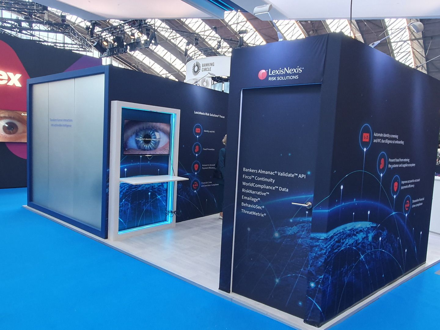 Perspectiva del stand de LexisNexis en Money20/20 Europe 2023 con iluminación azul y espacios de atención
