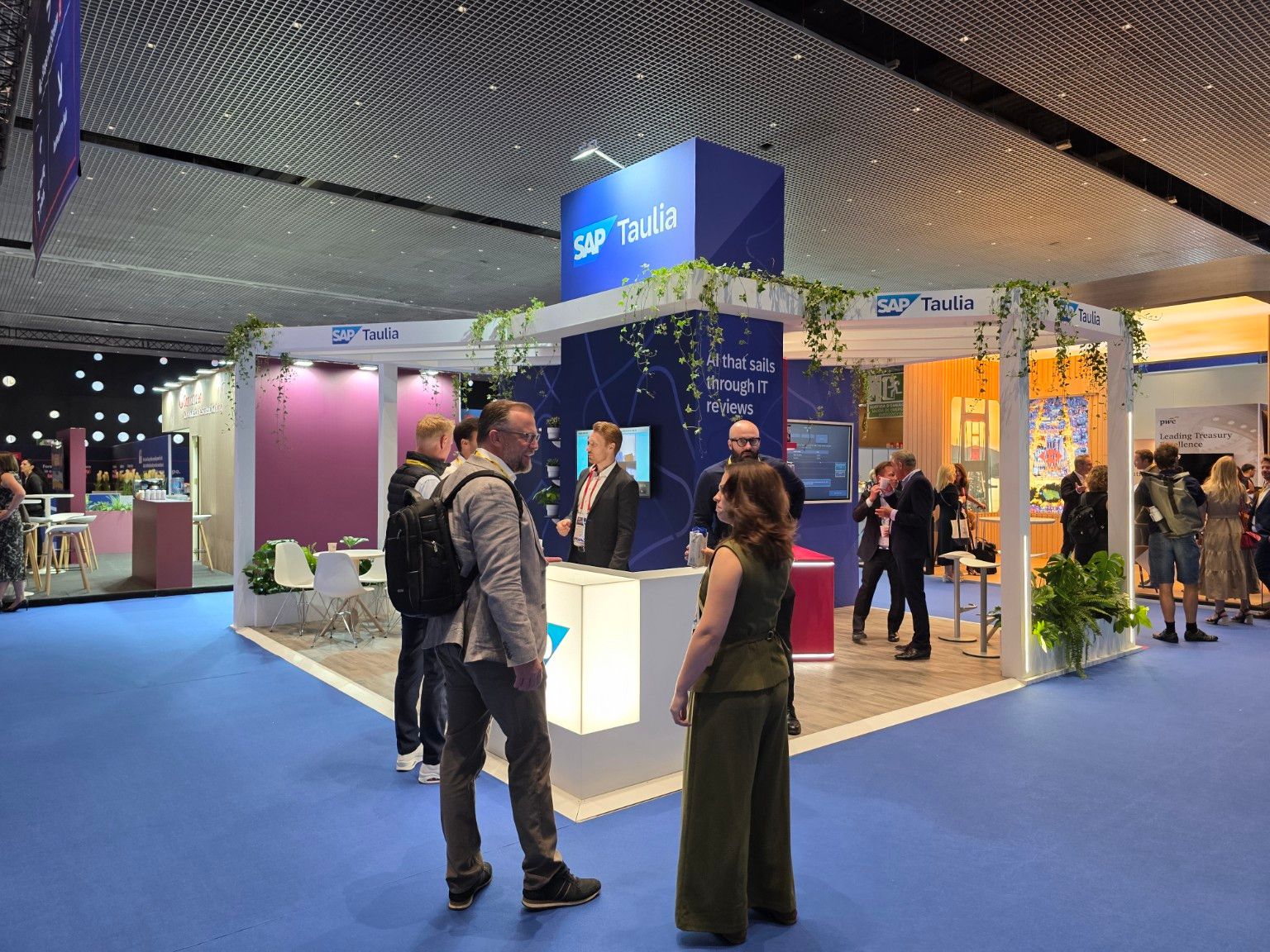 SAP Taulia stand at EuroFinance Barcelona 2026 with an illuminated counter, branding tower and hanging greenery