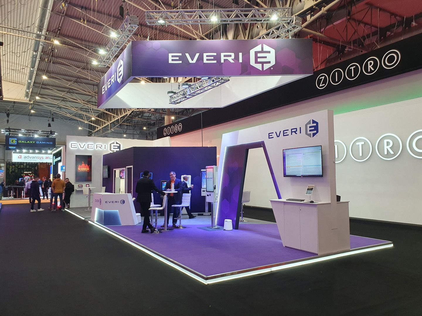 Overview of the Everi Payments stand at ICE Barcelona 2025, with purple suspended branding and illuminated platform
