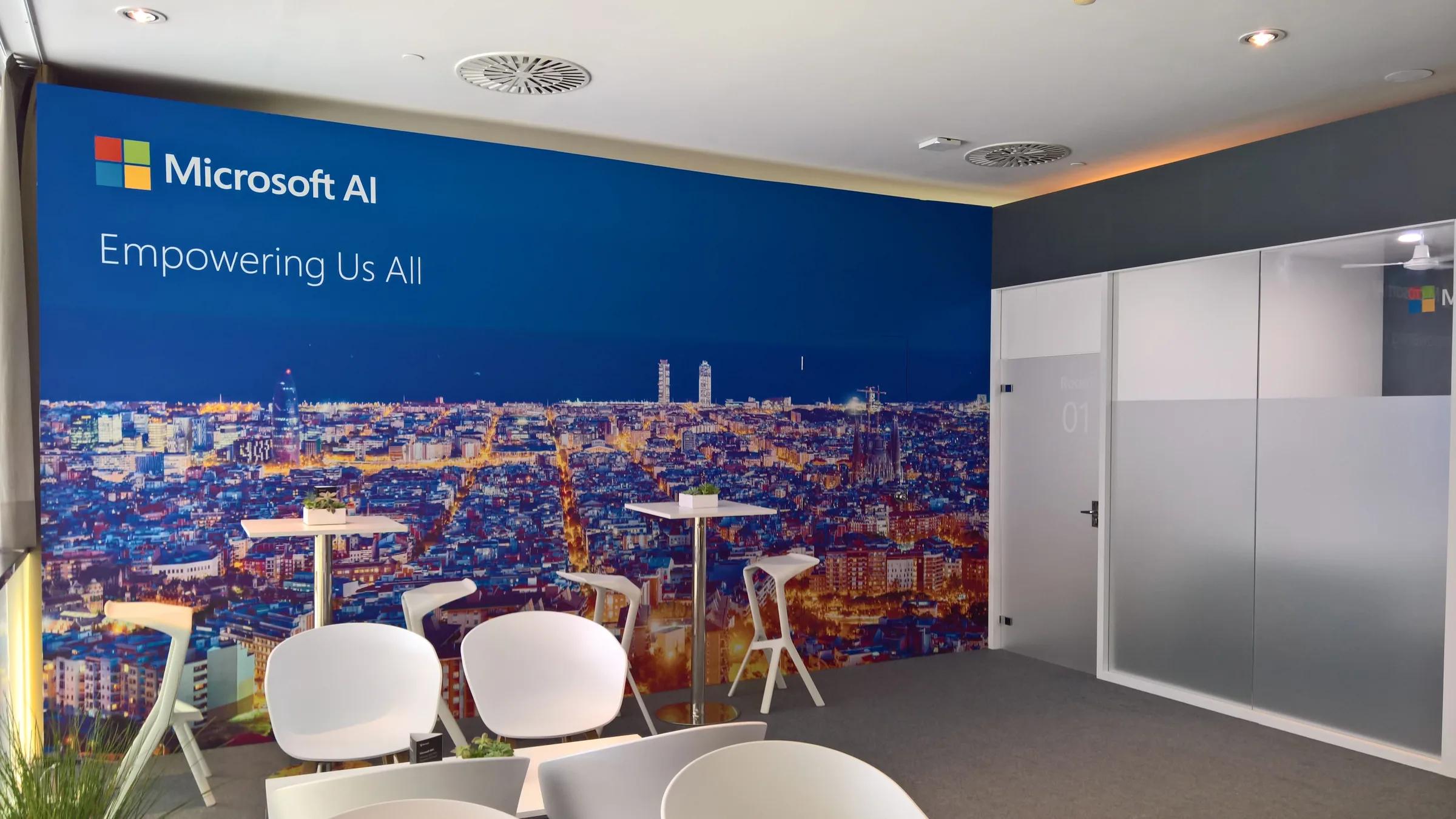 Sala de espera con asientos blancos y gráfica Microsoft AI · ITXPO 2018