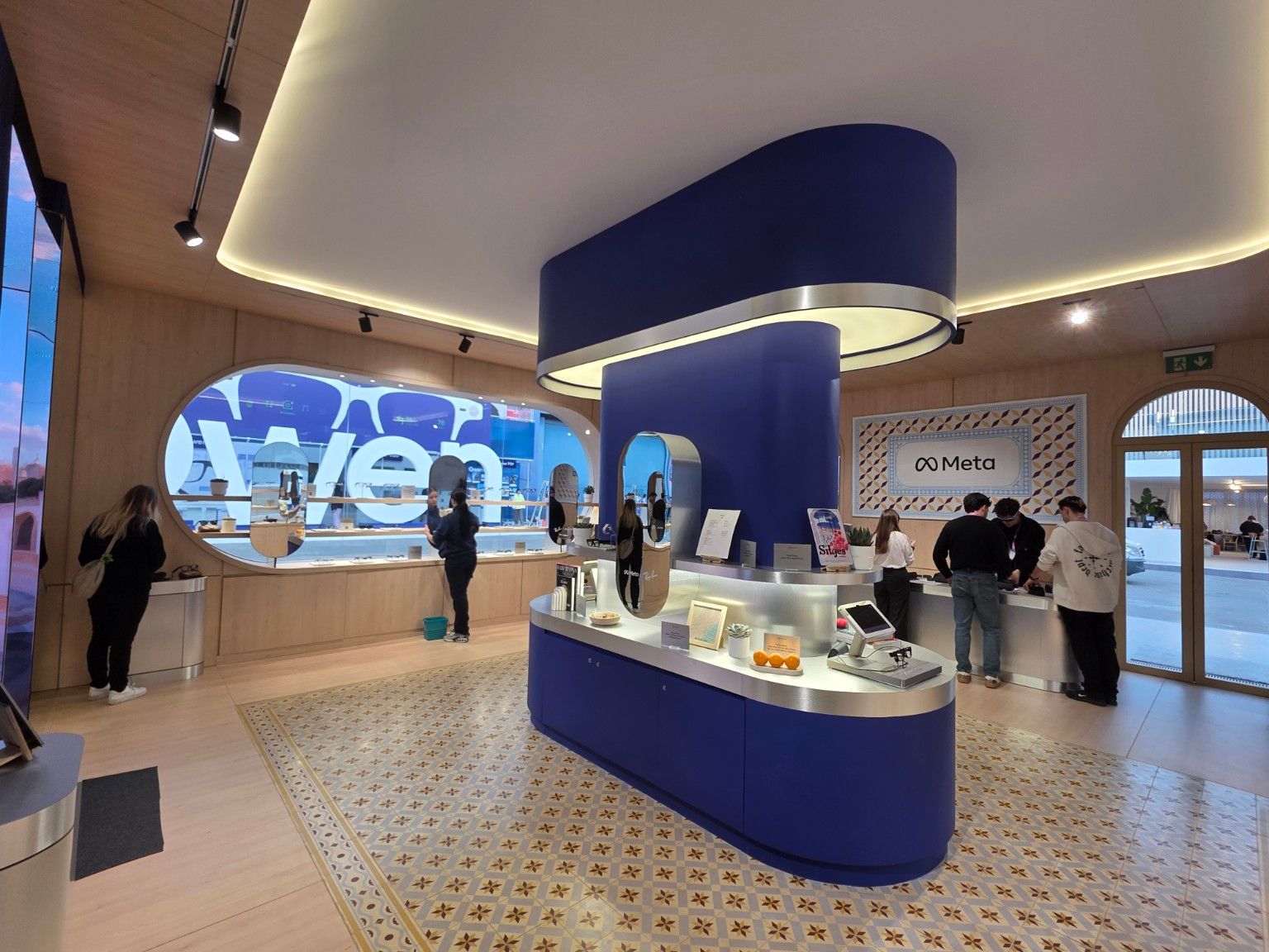 Central blue island with an illuminated overhead element and metallic finishes at the Meta stand